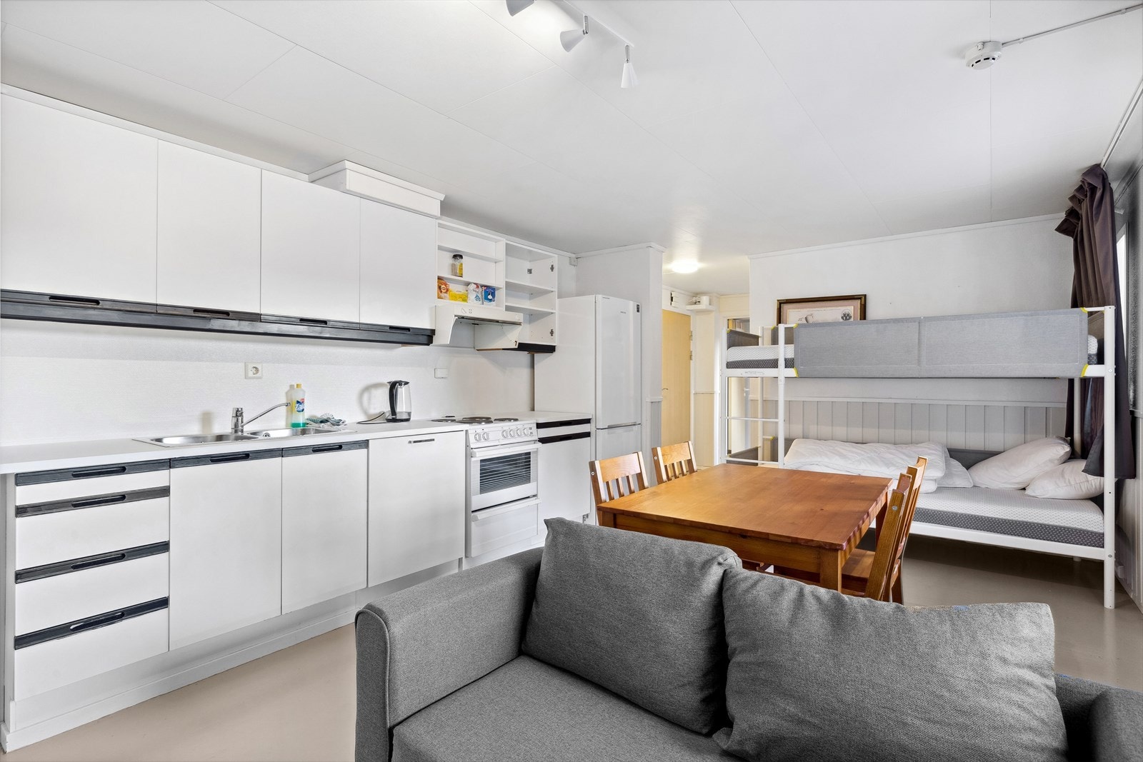 Kjøkkeninnredning med benkeplate i laminat, vask, komfyr, ventilator, oppvaskmaskin og kjøleskap Galleribilde