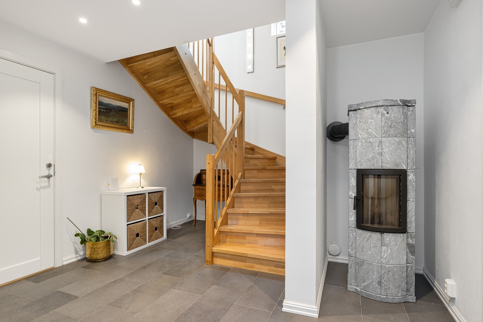 Romslig trappehall med flislagte gulv med gulvvarme og klebersteinsovn Galleribilde