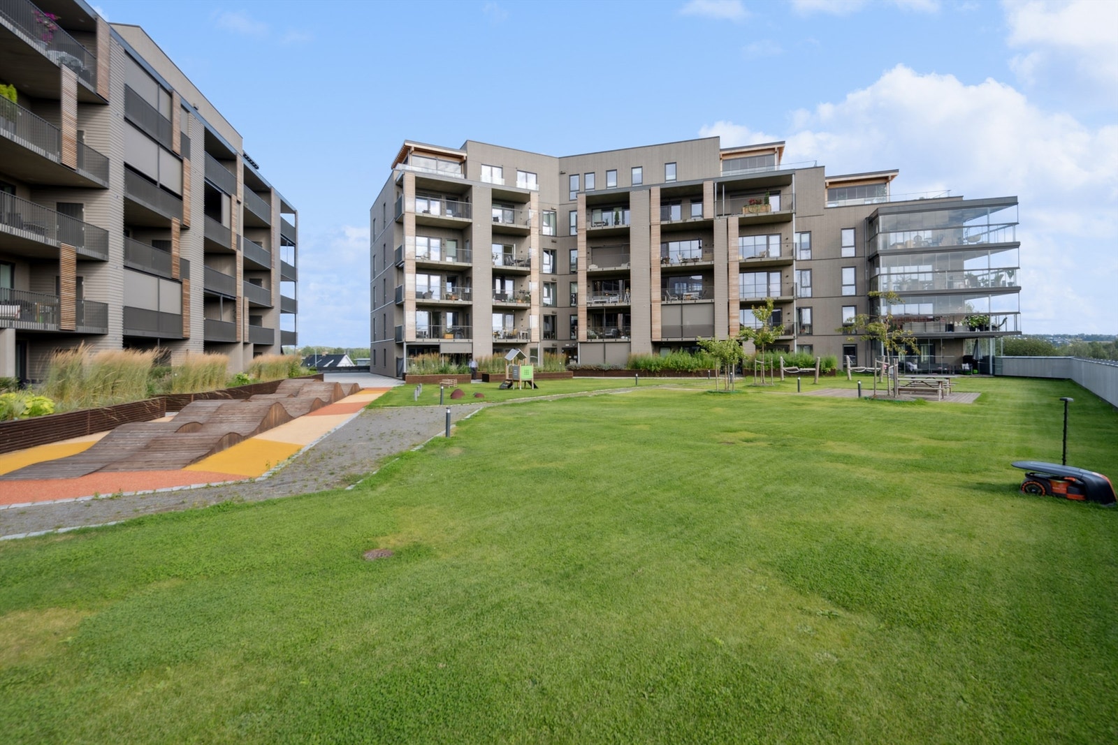 Atriet inne i sameiet er meget pent opparbeidet med plen, blomsterkasser, betongheller og lekeapparater. Galleribilde
