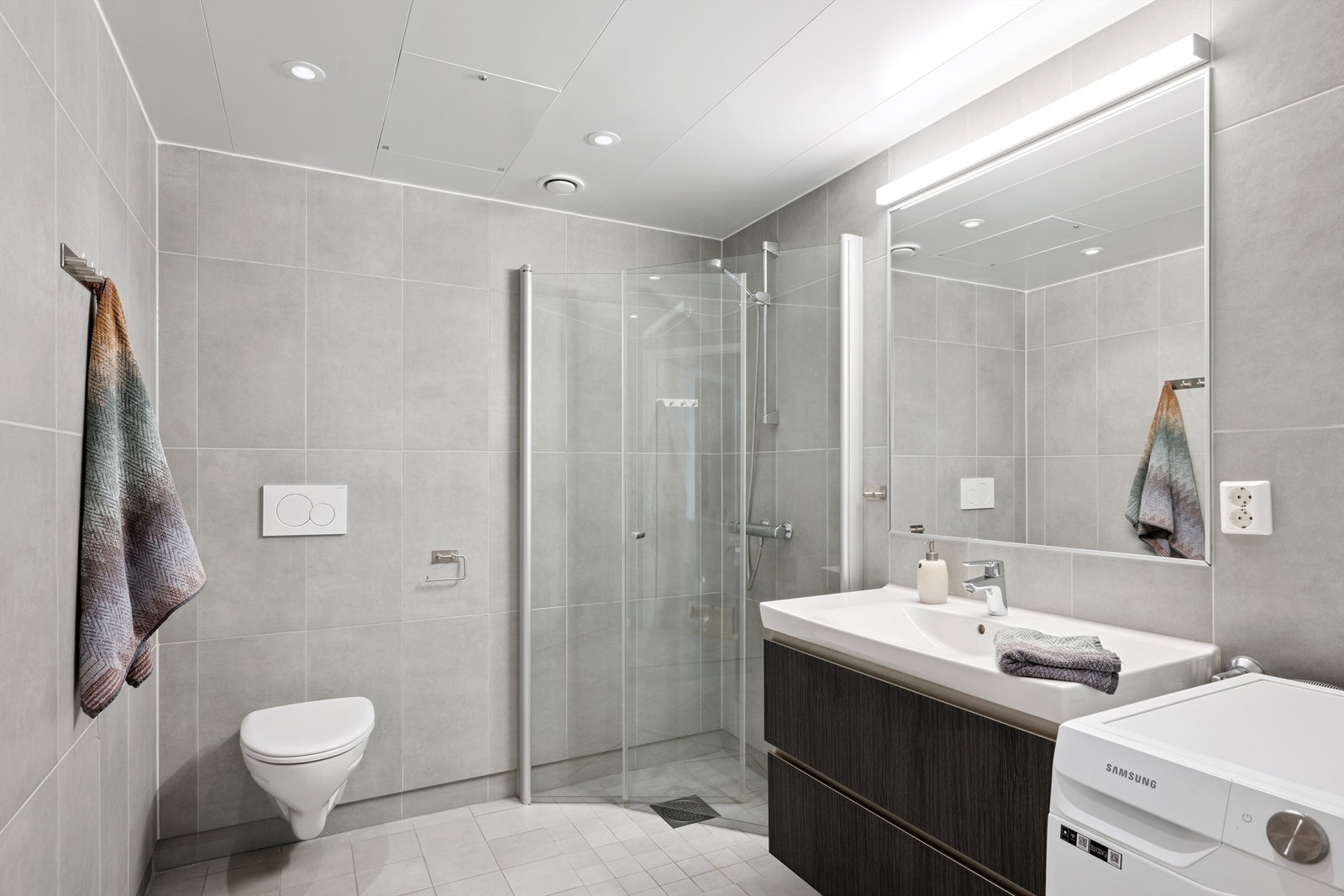 Badet er klargjort med opplegg for vaskemaskin og har innfellbare dusjdører. Galleribilde