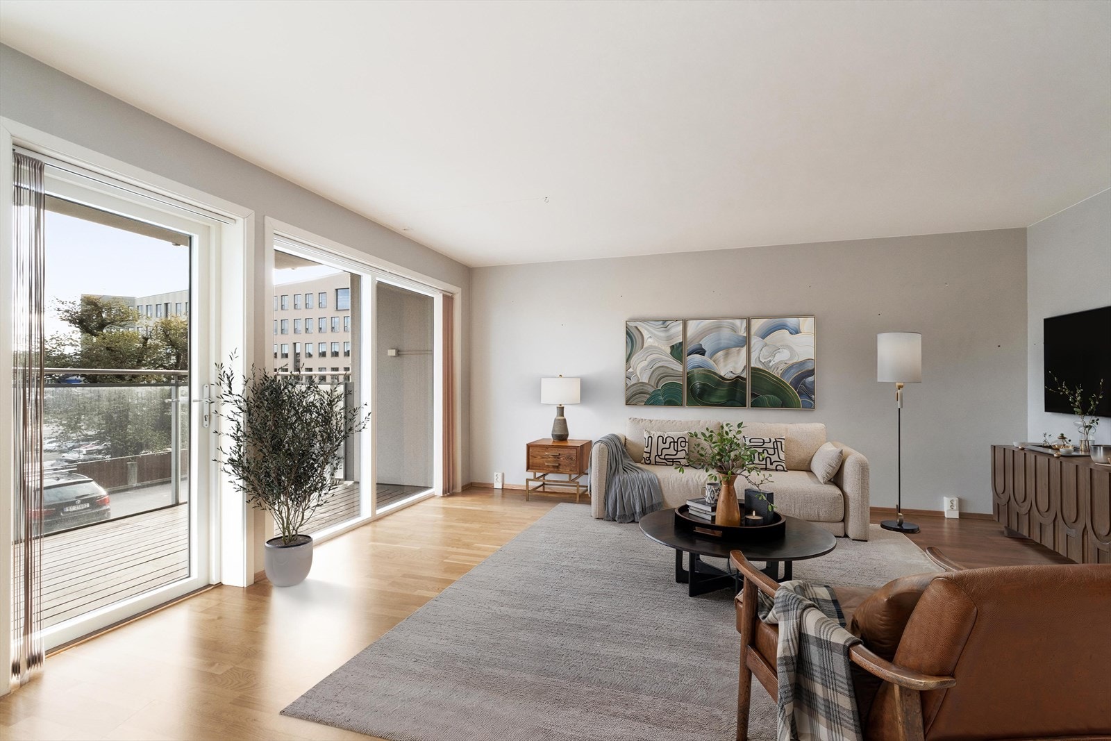 Leiligheten har en romslig stue med store vindusflater som gir utgang til balkong med glassrekkverk. (Bildet er digitalt møblert) Galleribilde