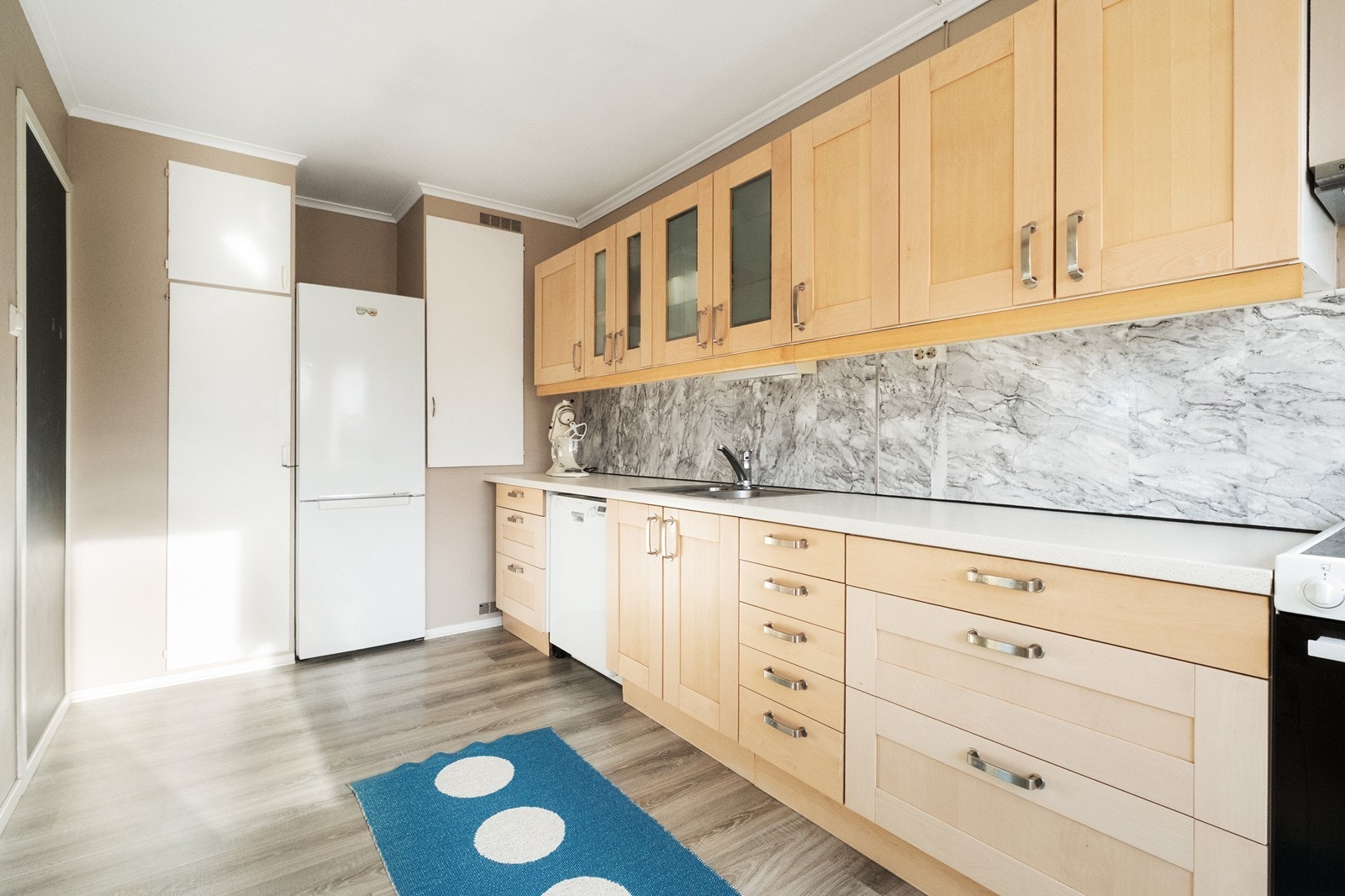 Tre-farget kjøkkeninnredning med profilerte fronter og laminat benkeplate gir en praktisk arbeidsflate. I veggen er det praktiske, integrerte skap. Galleribilde