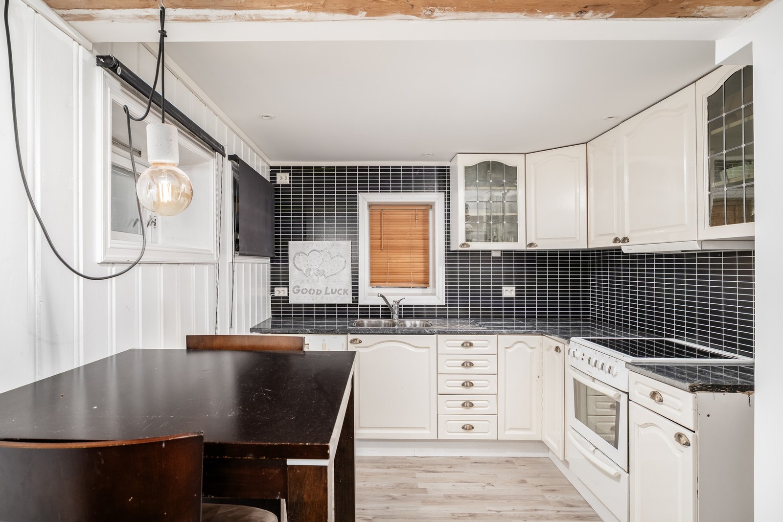 Kjøkkenet i underetasjen med eldre innredning som har profilerte fronter. Over komfyr er det montert ventilator. Galleribilde