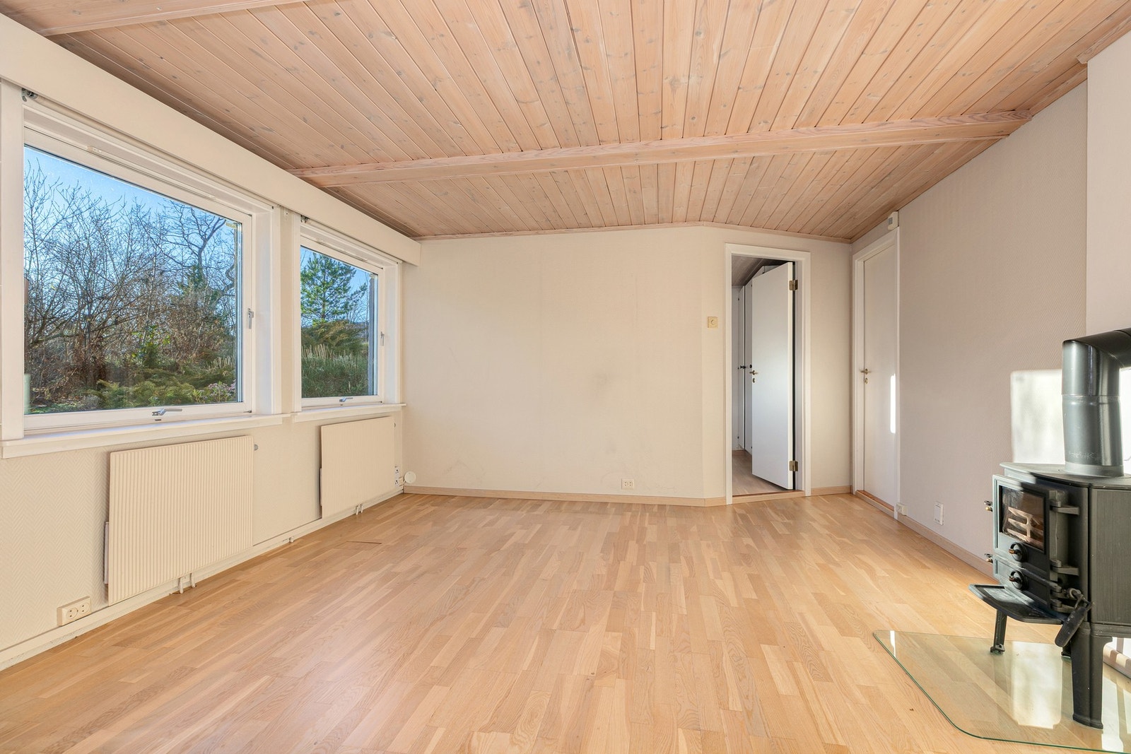 Sentralt i rommet står en liten peisovn med glass i fronten. Galleribilde