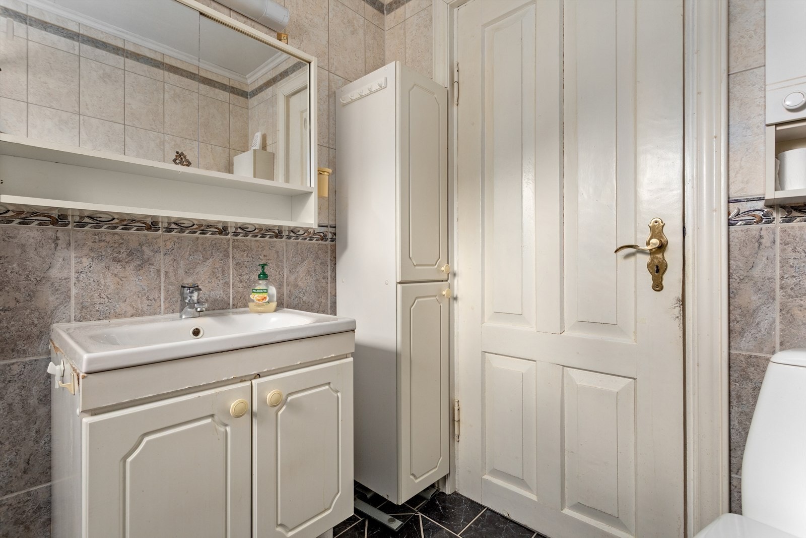 Badet inneheld klosett, nedfelt servant med underskåp, sideskåp, spegel og dusjhjørne med skyvedører. Galleribilde