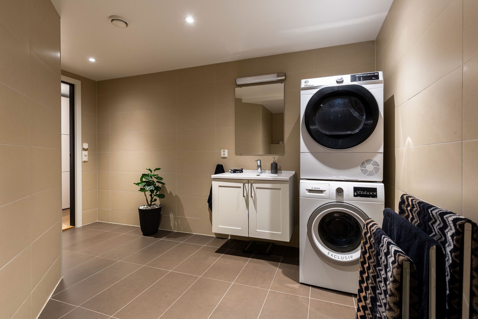 Den hvite baderomsinnredningen tilbyr god skapplass og en heldekkende servant, med speil og belysning montert over. Galleribilde