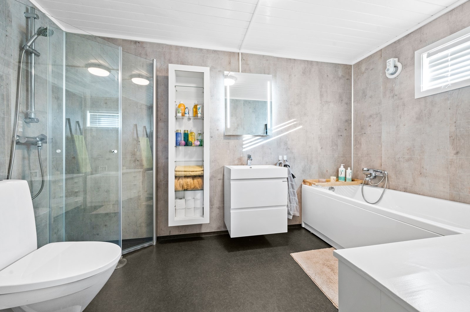 Lekkert bad med varmekabler i gulv, badekar, dusjhjørne, WC og servant. Galleribilde