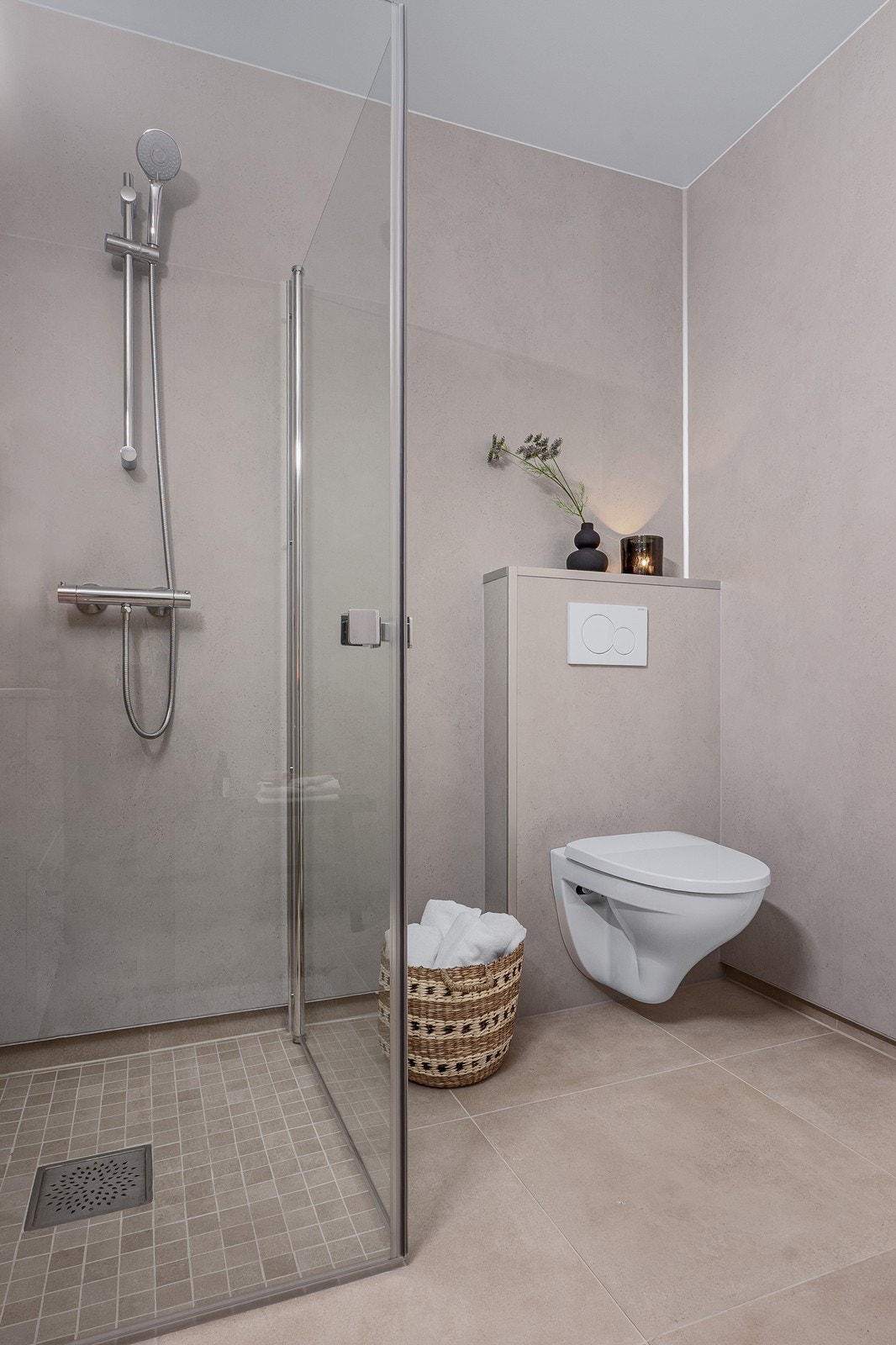 Badet er innredet med dusjnisje med glassdører, toalett, sevantskap med skuffer, speil, toalett og opplegg for vaskemaskin. Galleribilde