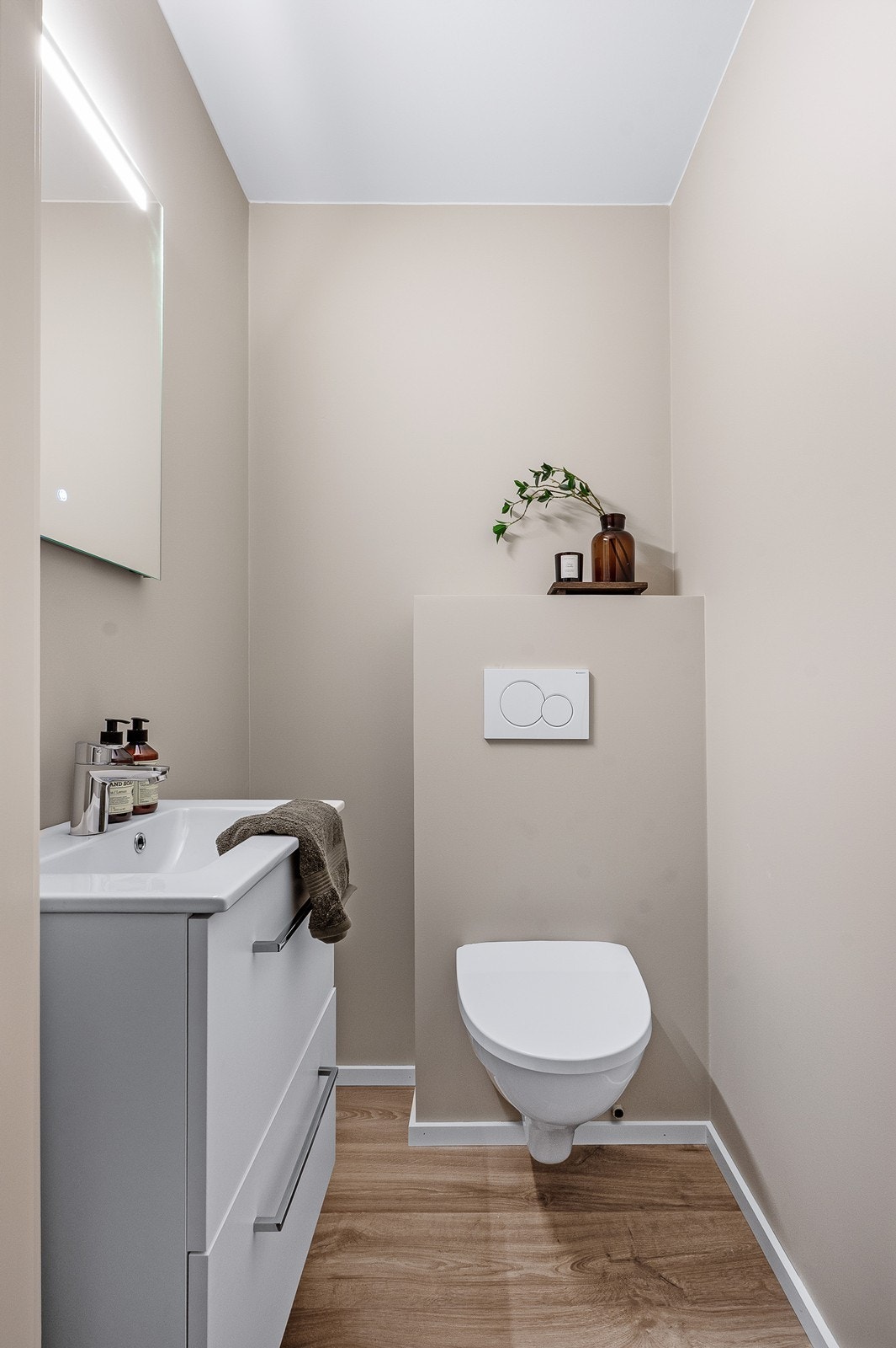 Toalettrommet er innredet med vegghengt toalett, servantskap med skuffer og speil med innfelt lys. Galleribilde