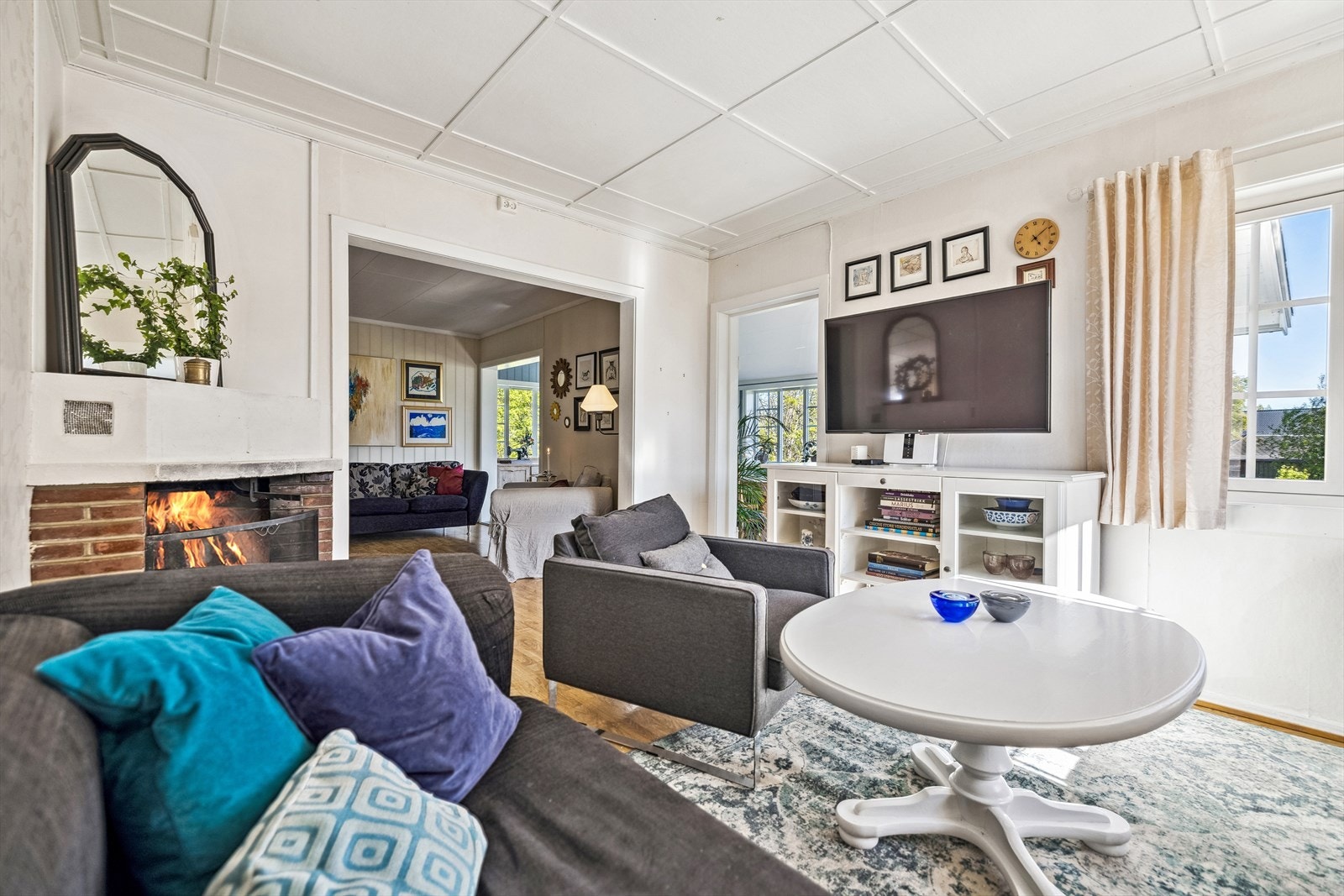 Den ene stuen har en sjarmerende gruepeis som er like trivelig også når det ikke er tent opp i peisen. Galleribilde