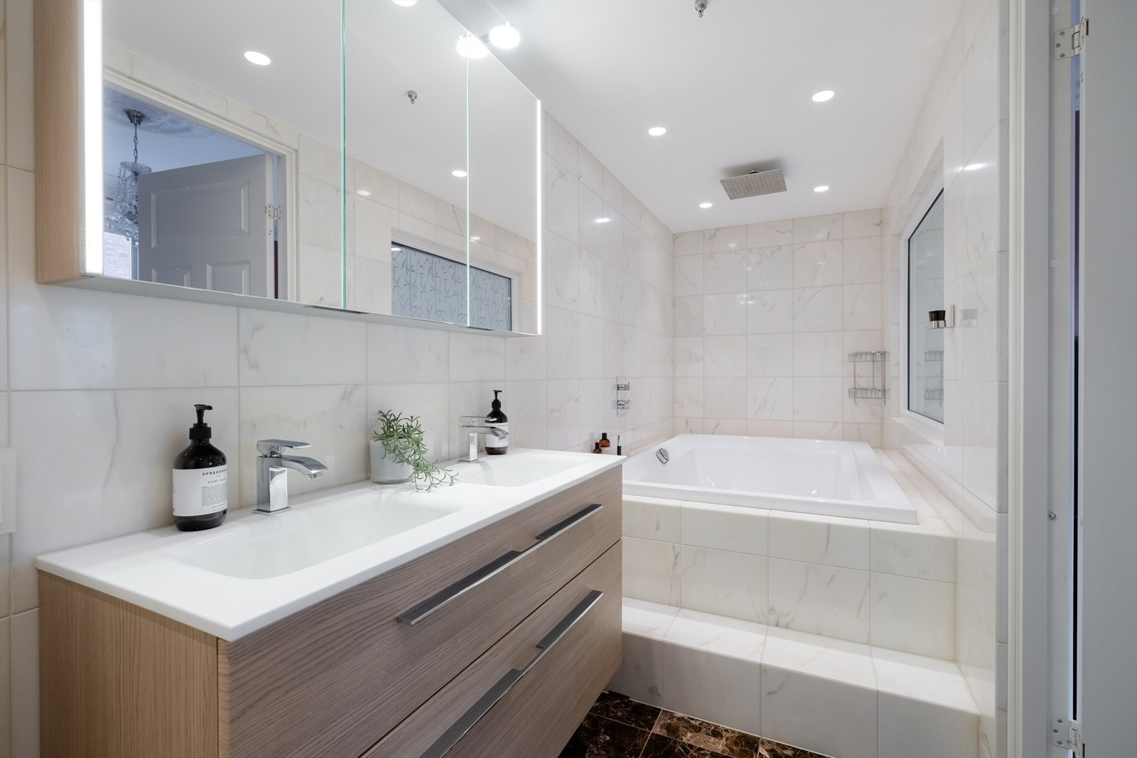 Speilskap med lysarmatur på vegg over servant. Veggmontert toalett. Tapp-well blandebatteri og Tap-well regnfallsdusj. Galleribilde