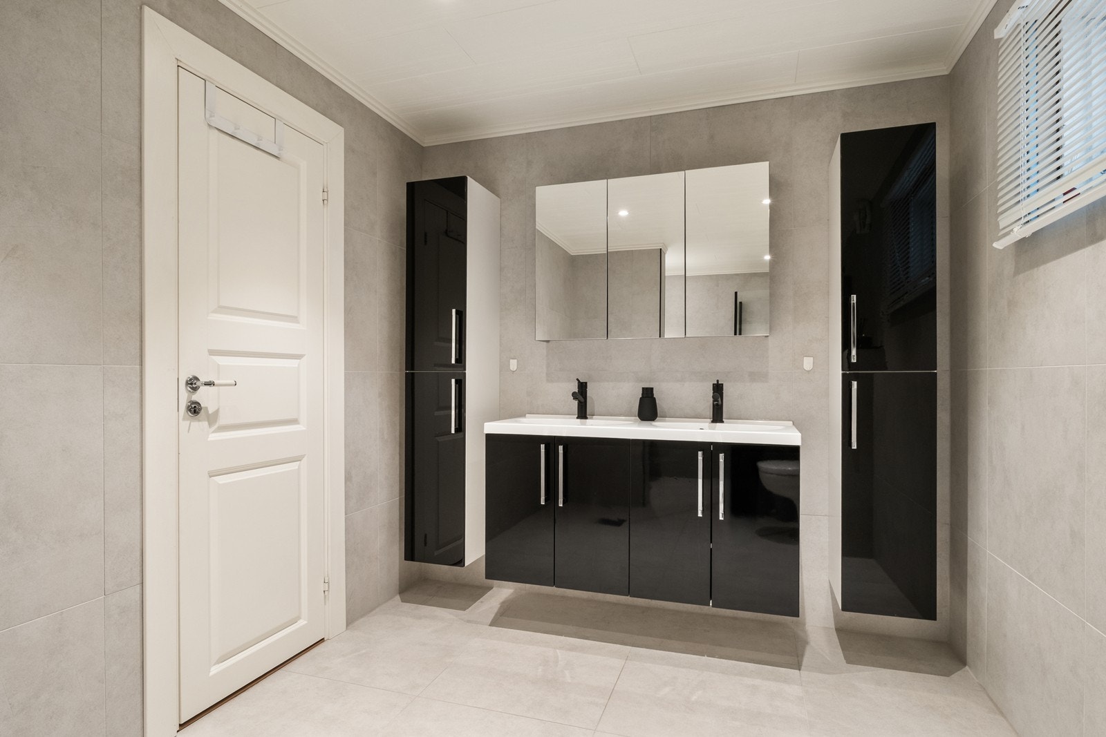 Flislagt bad med innholdsrik baderomsinnredning med dobbel servant og mye skapplass. Galleribilde