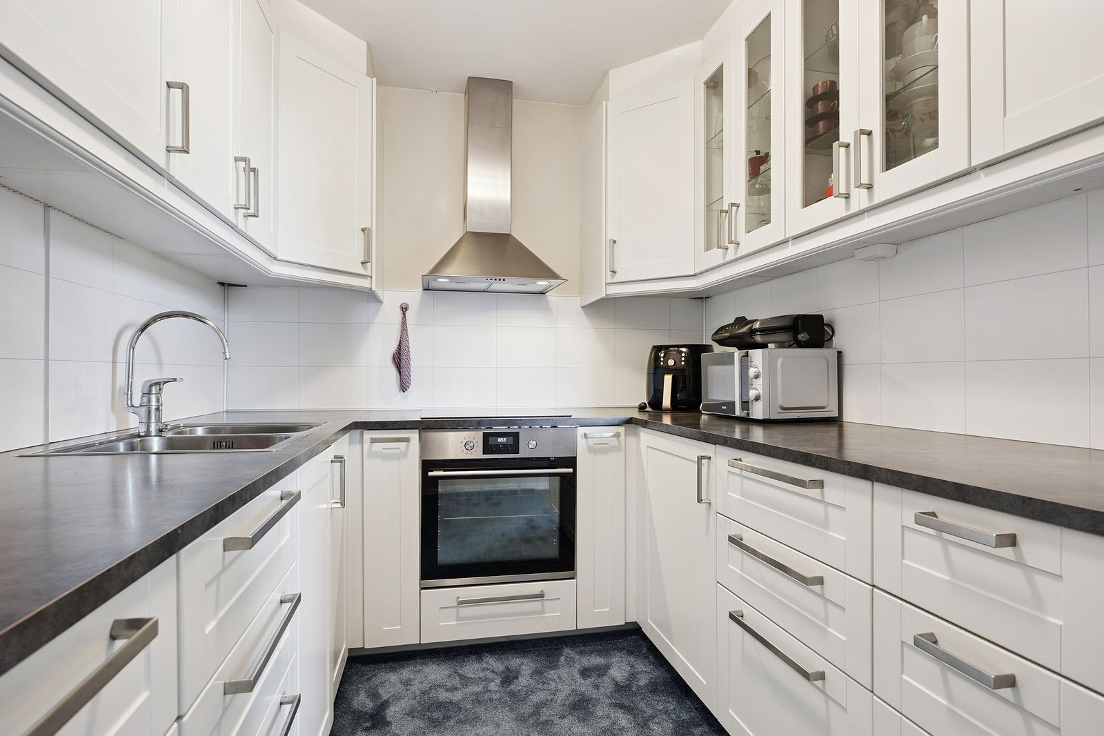 Kjøkken med godt med skap- og benkeplass og integrerte hvitevarer Galleribilde