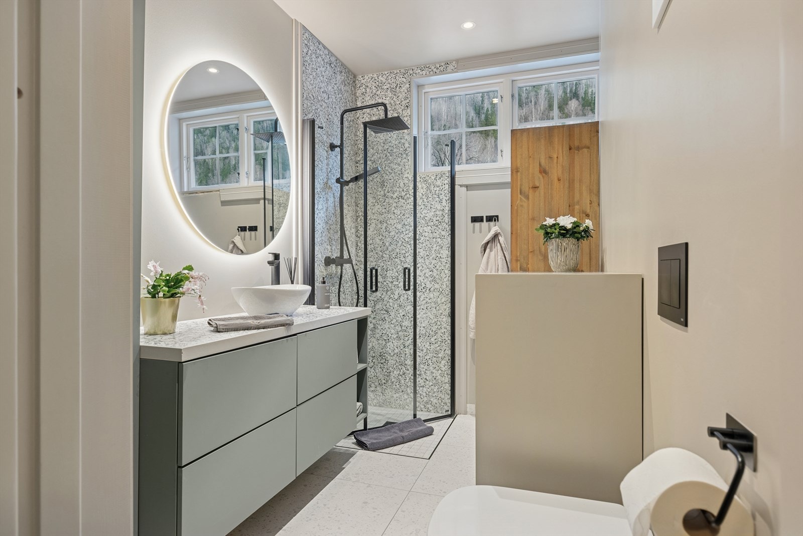Rommet er innredet med stilrene detaljer og praktiske løsninger som gjør hverdagen enklere. Her finner du et dusjhjørne med god plass, WC og en elegant baderomsinnredning med vask og speil. Galleribilde