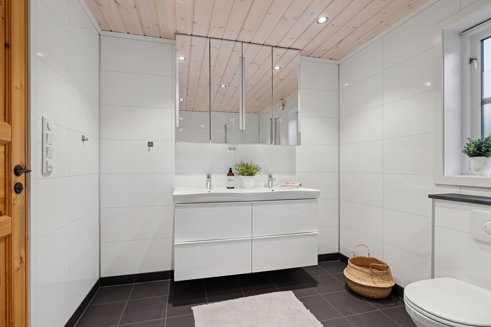 Lyst og stilrent baderom med stor servantseksjon og speilskap som gir rikelig oppbevaringsplass. Praktiske løsninger som holder rommet ryddig og funksjonelt. Galleribilde