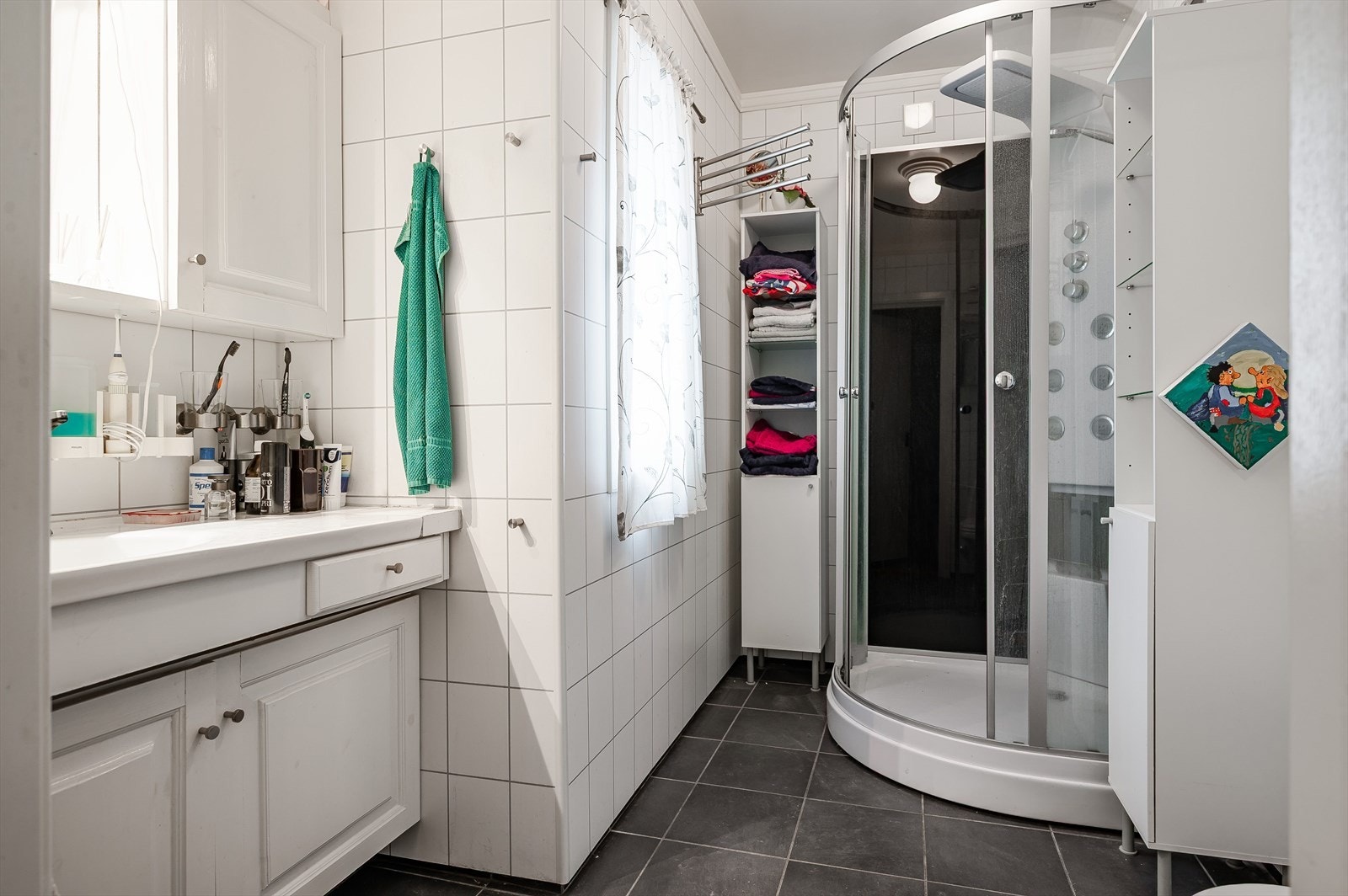 Badet har dusjkabinett, toalett, servant med speil og skap. Galleribilde