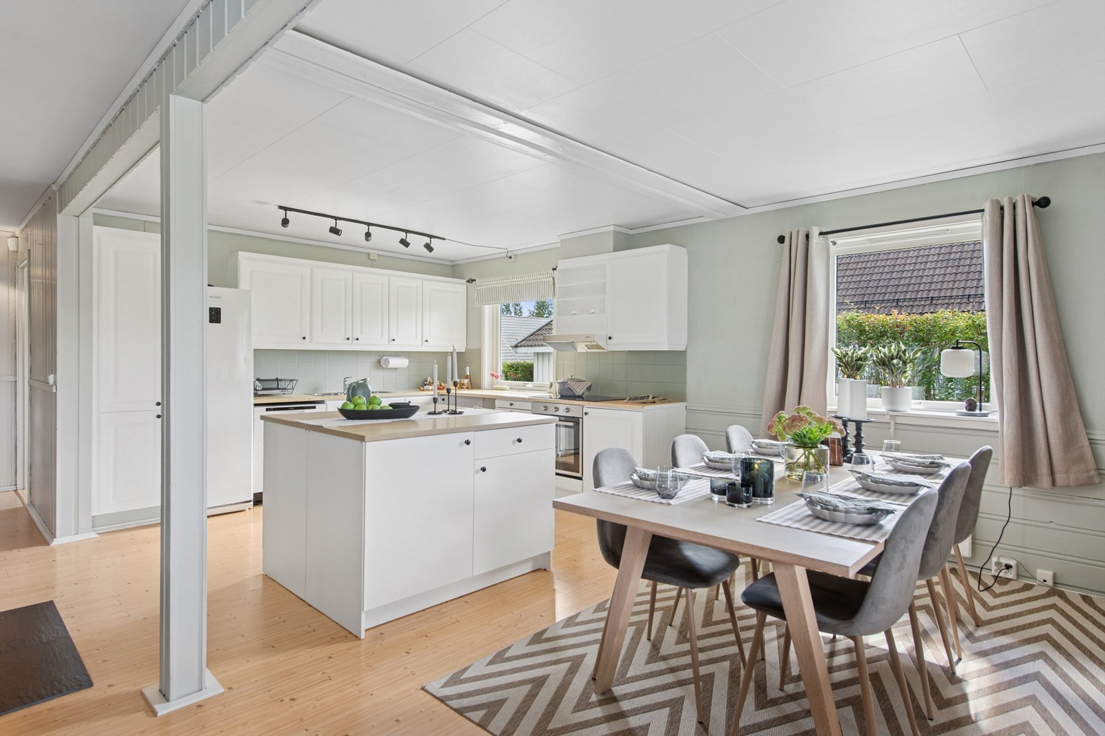 Åpen løsning mellom stue og kjøkken. En praktisk kjøkkenøy danner et naturlig skille mellom rommene. Galleribilde