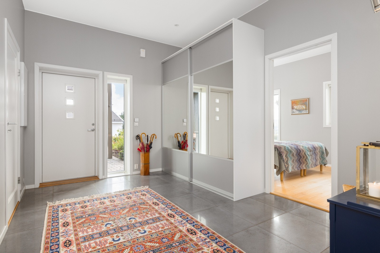 Du kommer inn i en romslig og innbydende entré med flislagt gulv og behagelig gulvvarme. Her er det god plass til sko og yttertøy i en stor skyvedørsgarderobe med speilfelt. Galleribilde