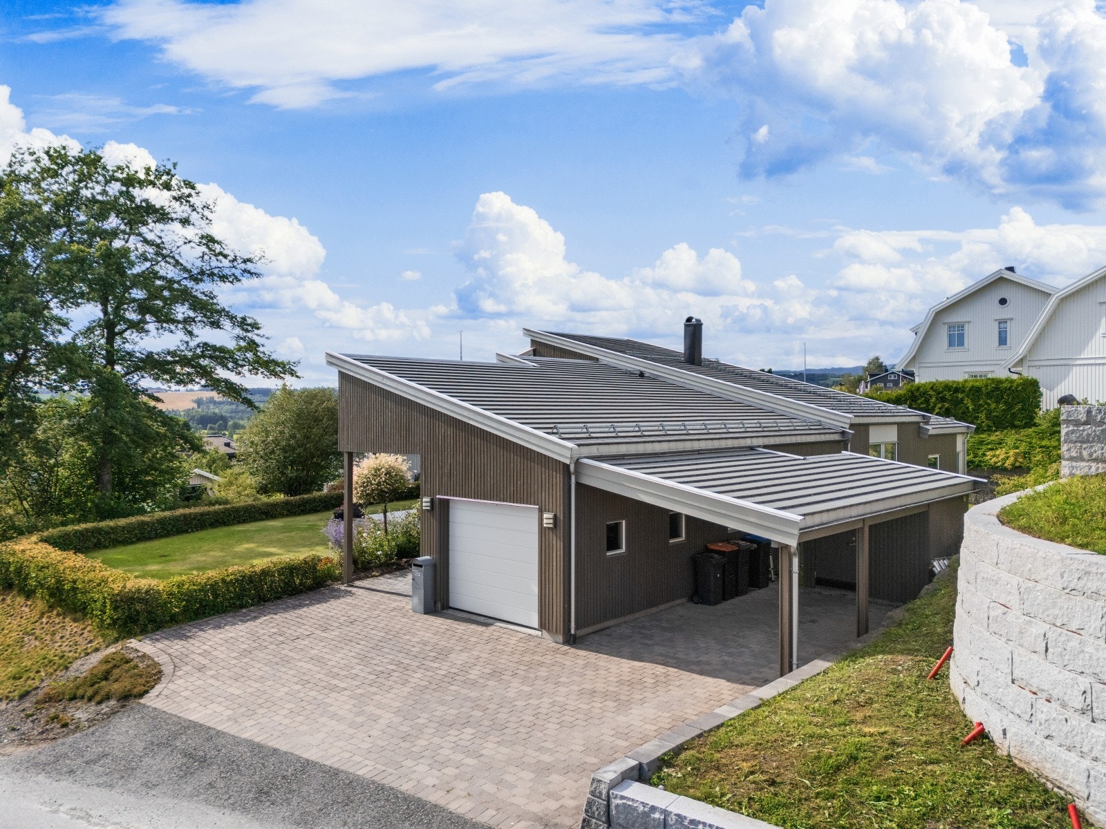 Boligen har inntilbygget garasje på 19m², samt inntilbygget carport og utvendig bod på 4m². Tomten er lettstelt og pent opparbeidet med belegningsstein i gårdsplassen. Forstøtningsmurer av betongstein. Hagen er innhegnet med hekk og opparbeidet med plen. Galleribilde