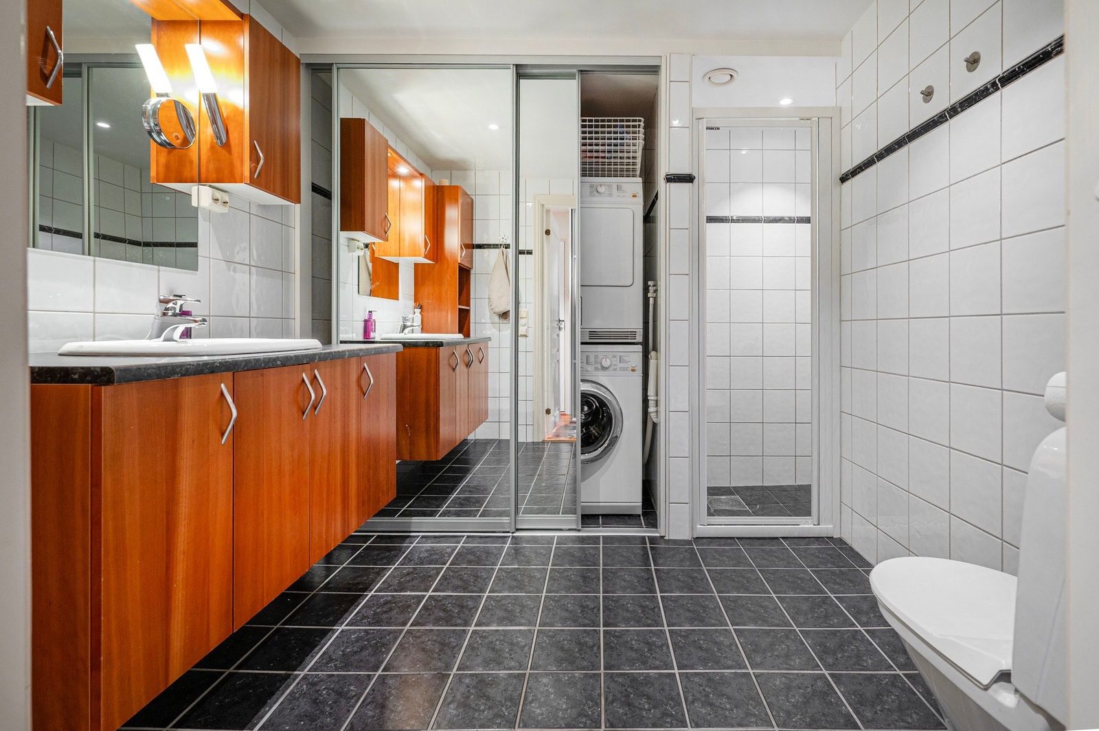 Romslig helfliset bad med dusjnisje og garderobeløsning/dører som skjuler vaskemaskin mm. Galleribilde