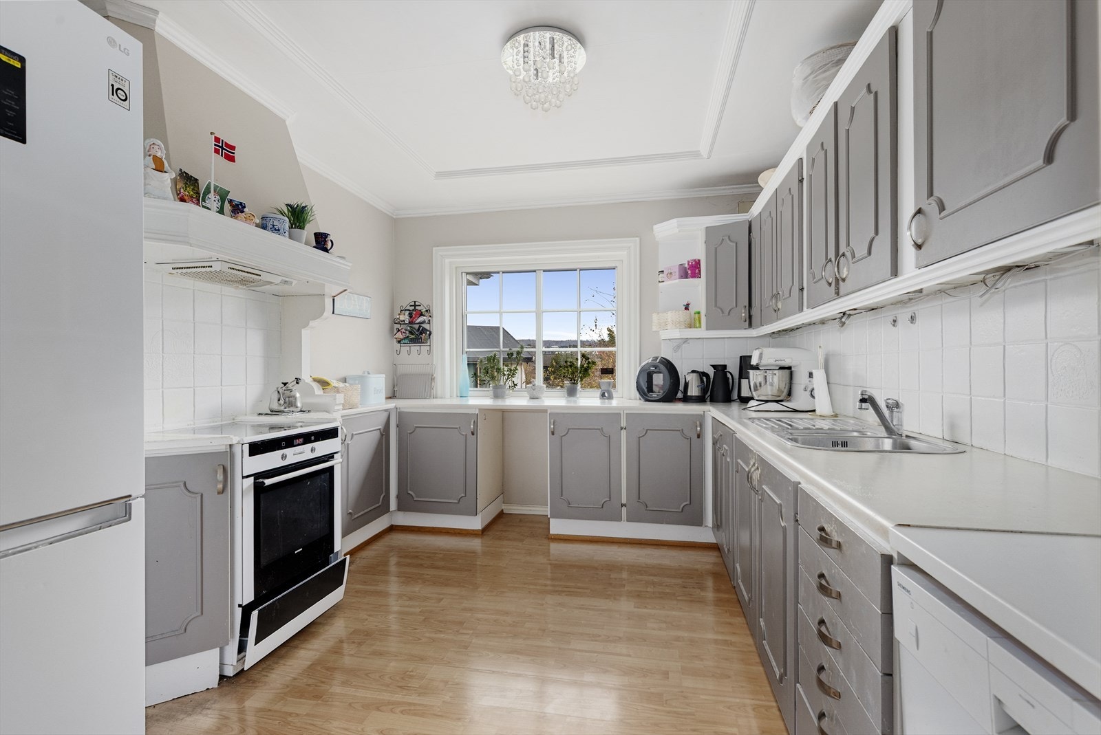 Romslig kjøkken med god skapplass på flere sider av rommet. Det er opplegg for oppvaskmaskin og ventilator over koketopp. Galleribilde