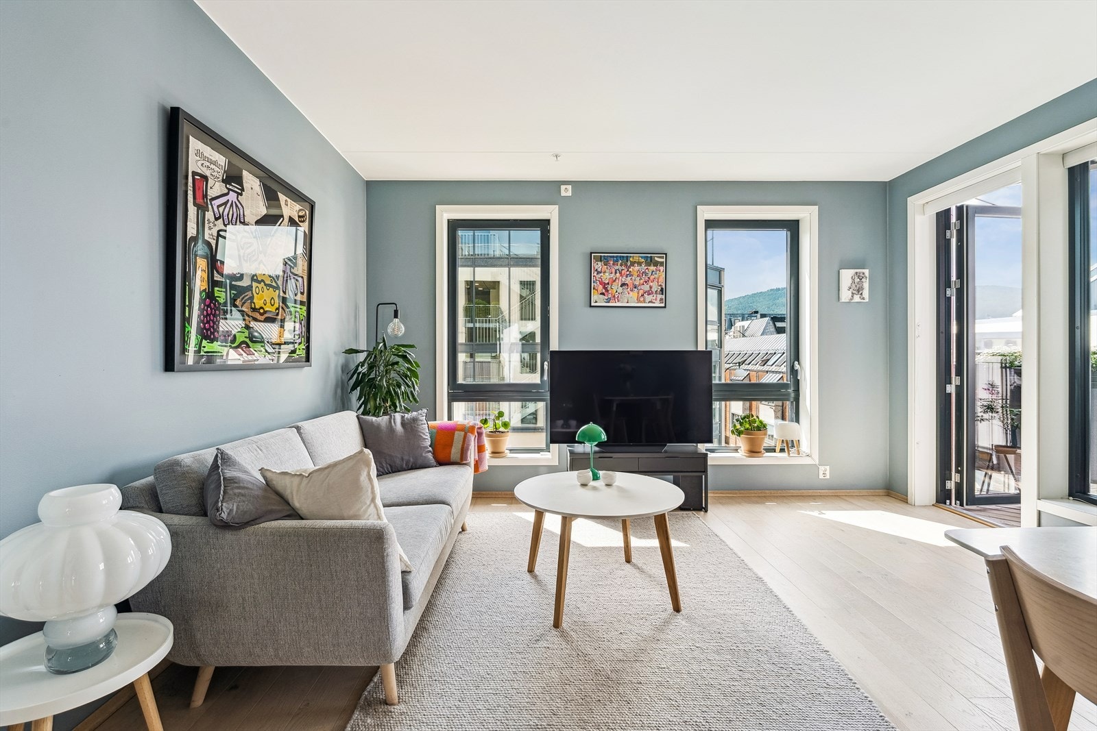 Lys og innbydende stue med en-stavs parkett på gulv og malte, slette vegger. Galleribilde