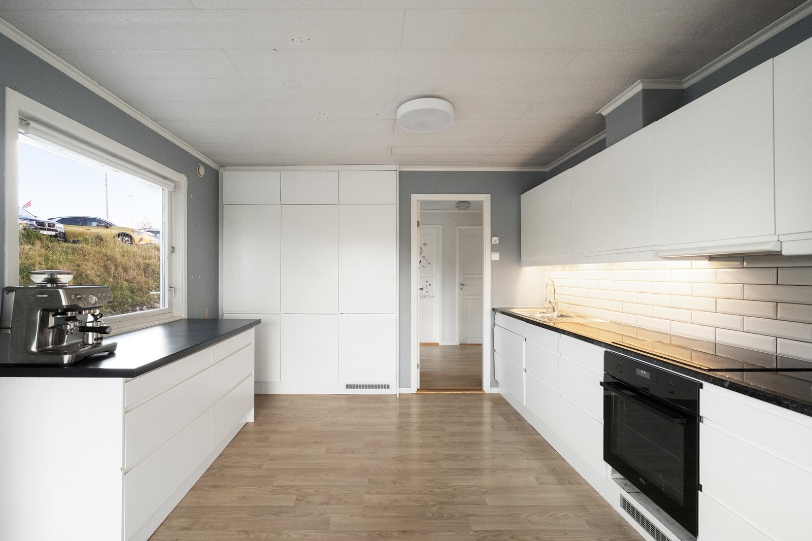 Kjøkkeninnredning i tidløs design, med hvite, glatte fronter og integrerte hvitevarer. Galleribilde