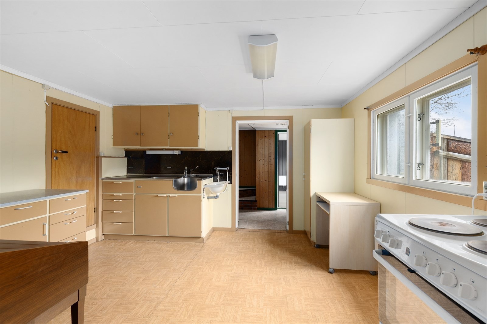 Kjøkkenet har en eldre, takhøy innredning med slette fronter, samt benkeplate i laminat og stålbeslag. Galleribilde