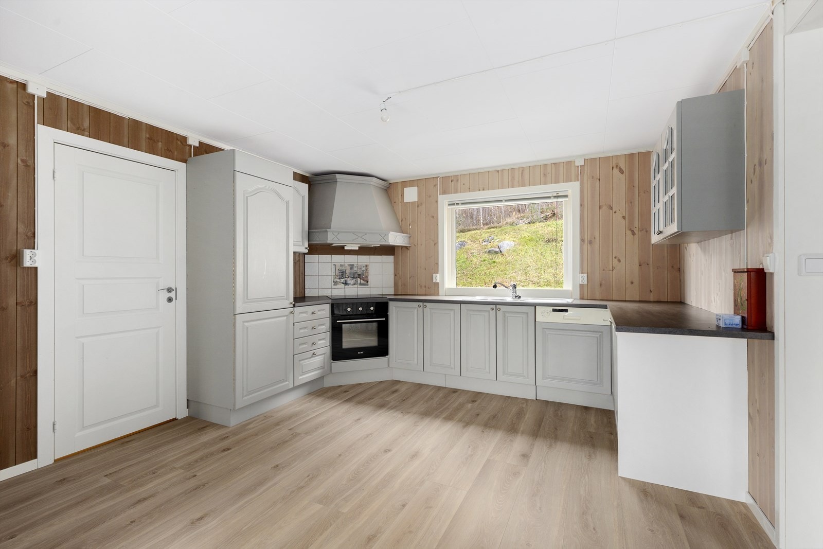 Kjøkkendelen har en pen innredning med profilerte fronter og noe glasskap, benkeplate av laminat og flis over deler av kjøkkenbenk. Galleribilde