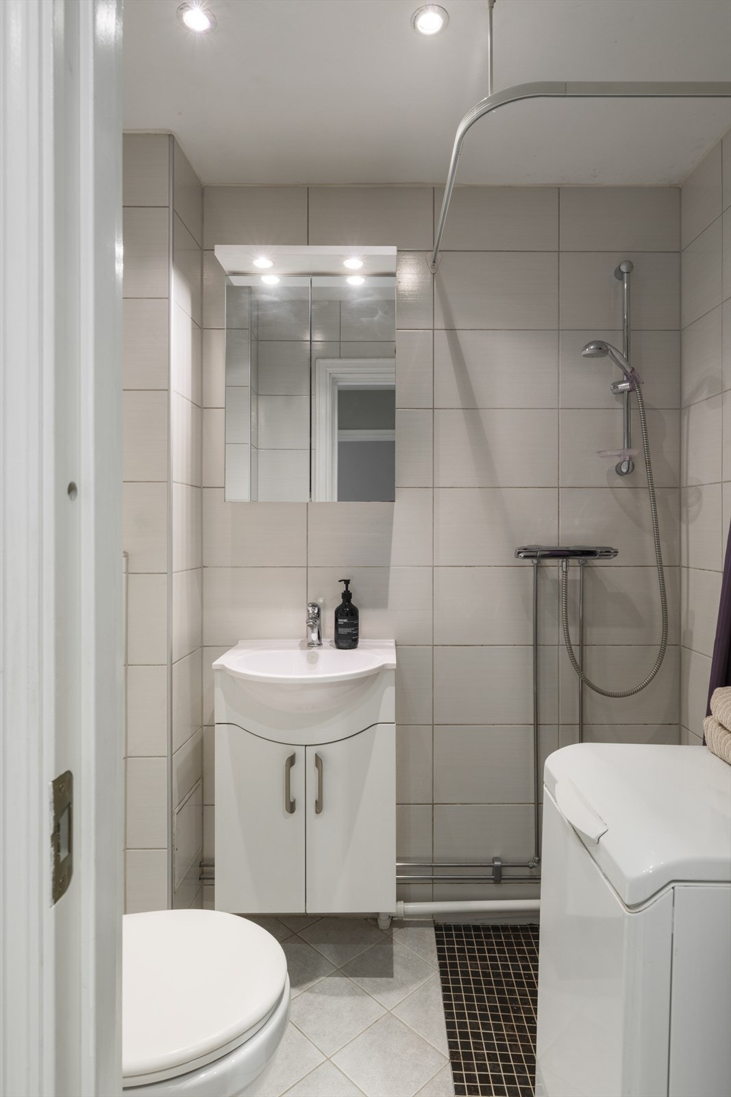 Badet har dusjhjørne, servant med skap, vegghengt speilskap og vegghengt toalett, i tillegg til opplegg for smal vaskemaskin. Galleribilde
