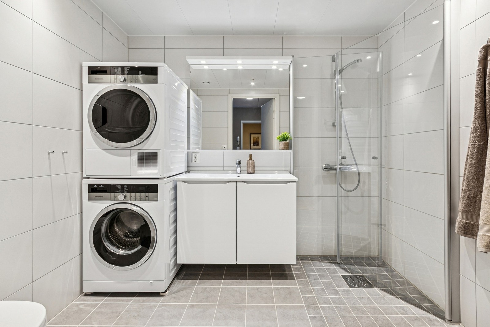 Flislagt baderom med downlights i himling, vegghengt WC og dusjnisje med glassvegger. Galleribilde