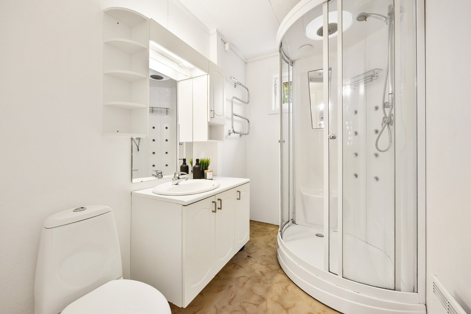 Badet i hovedetasjen har dusjkabinett, vegghengt servant med belysning og et gulvstående klosett Galleribilde