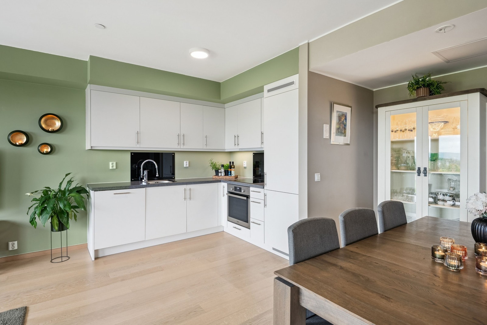 Kjøkken med glassplater på vegg bak oppvaskkum og platetopp for lettere renhold inkl. led-lys oppunder overskap. Galleribilde