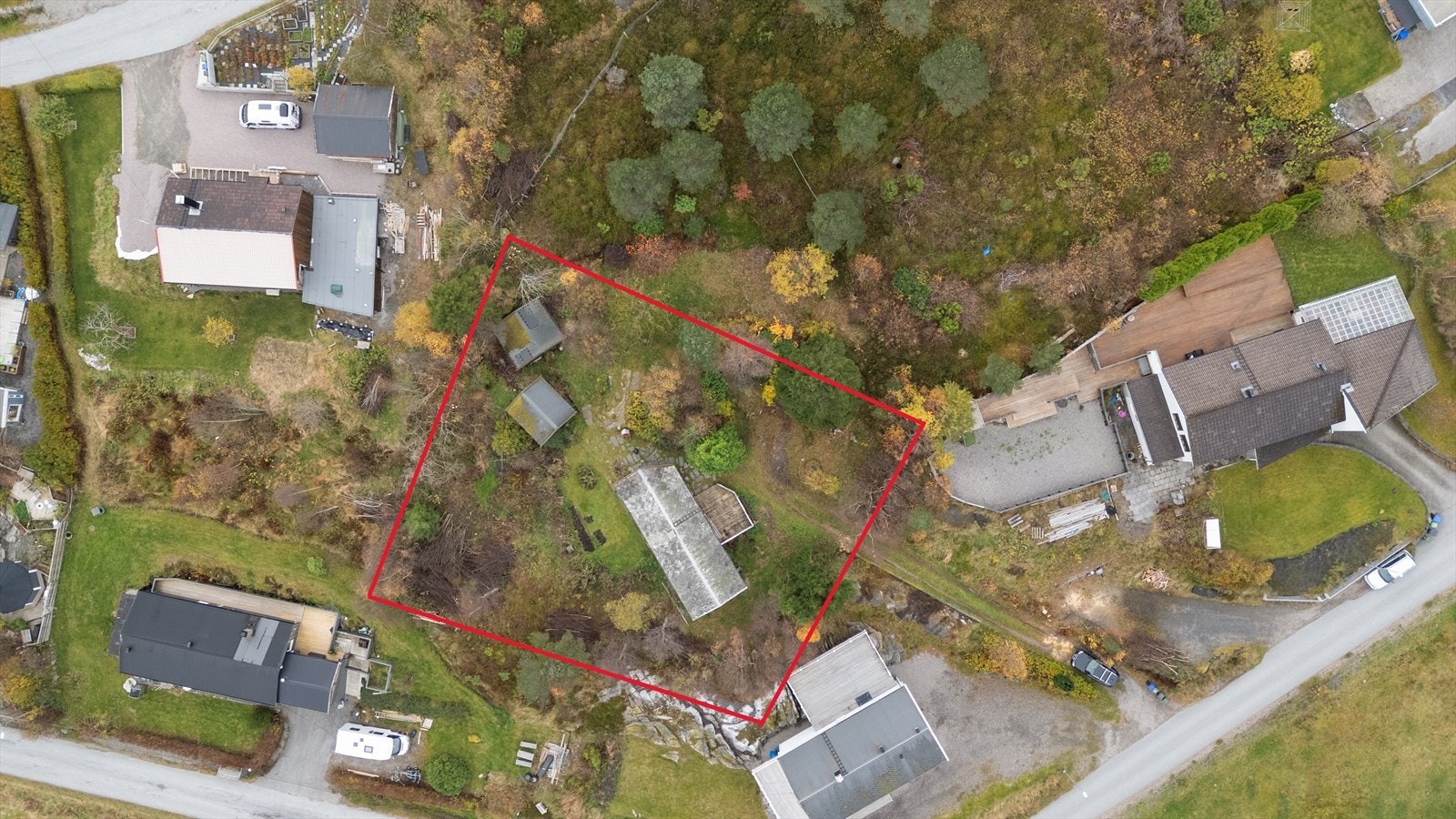 Dronefoto over eiendommen og nærområdet. 120/228 omtrentlige tomtegrenser, ihht. kommunens grunnkart, avmerket med rødt. Galleribilde
