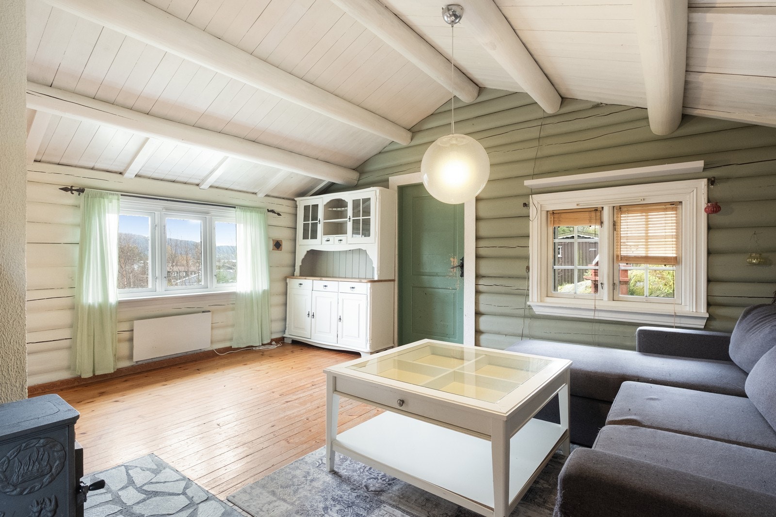 Stuen er åpen og romslig, og vinduene gir dagslys og utsikt mot fjell og grøntområder. Galleribilde