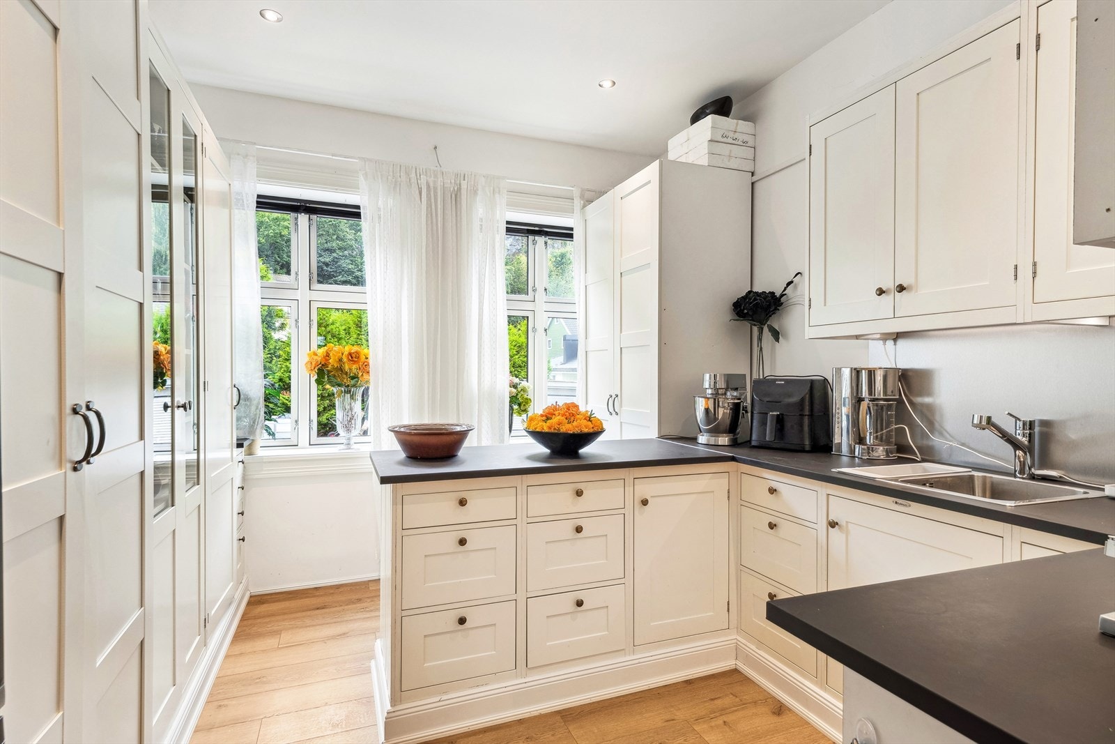 Grovkjøkken med hvit profilert innredning som har godt med skaper og benkeplass. Galleribilde