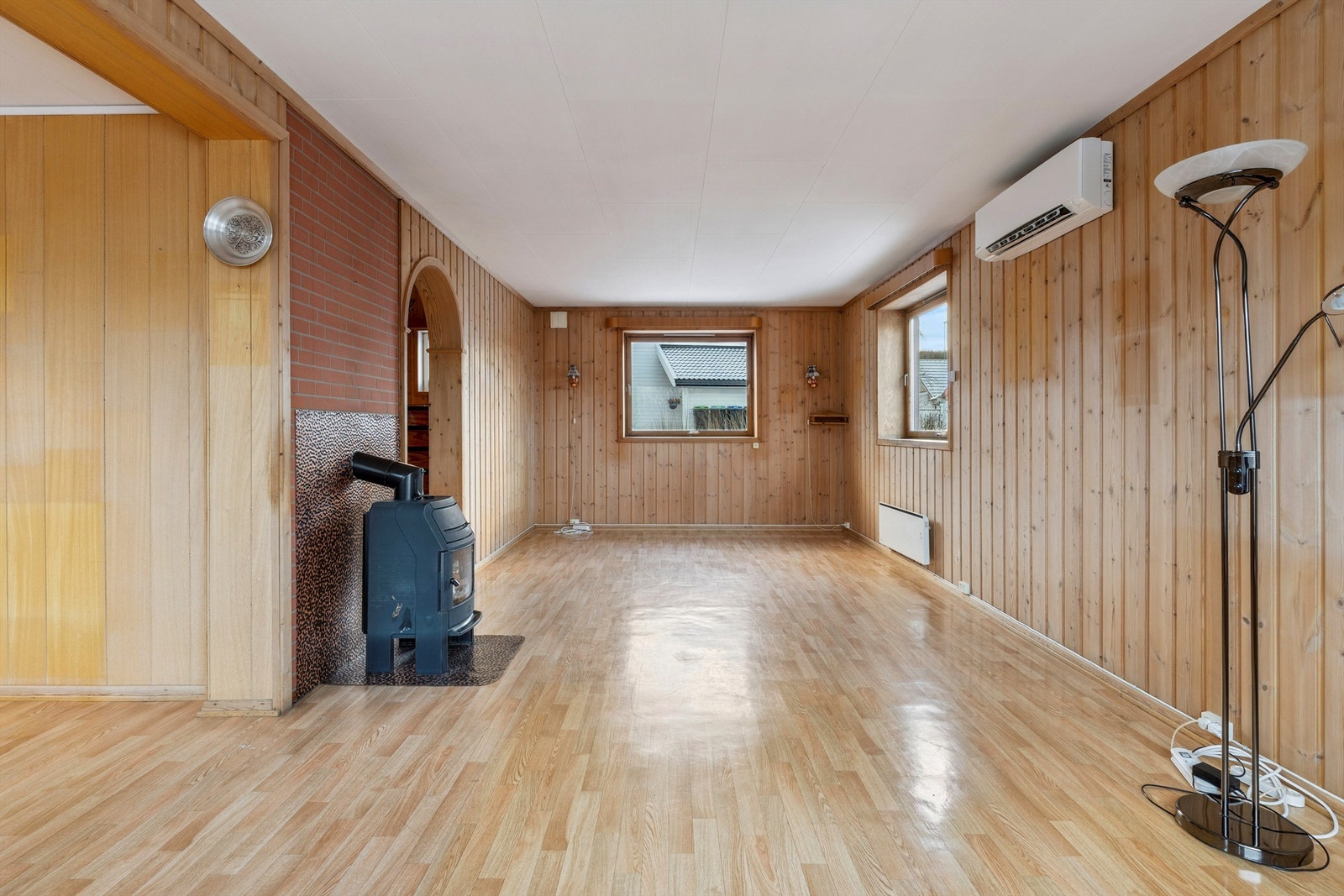 Romslig stue med plass til flere møbelgrupper og panelkledde vegger. Galleribilde