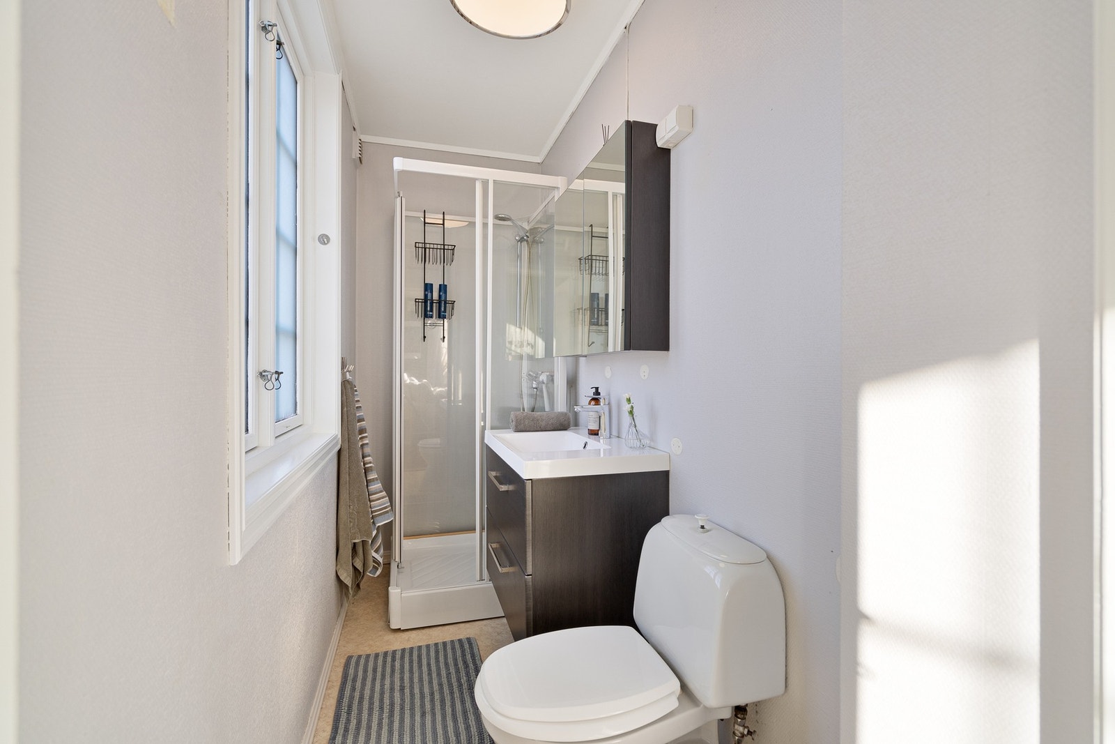 Badet inneholder dusj, servant innredning, toalett og speilskap Galleribilde