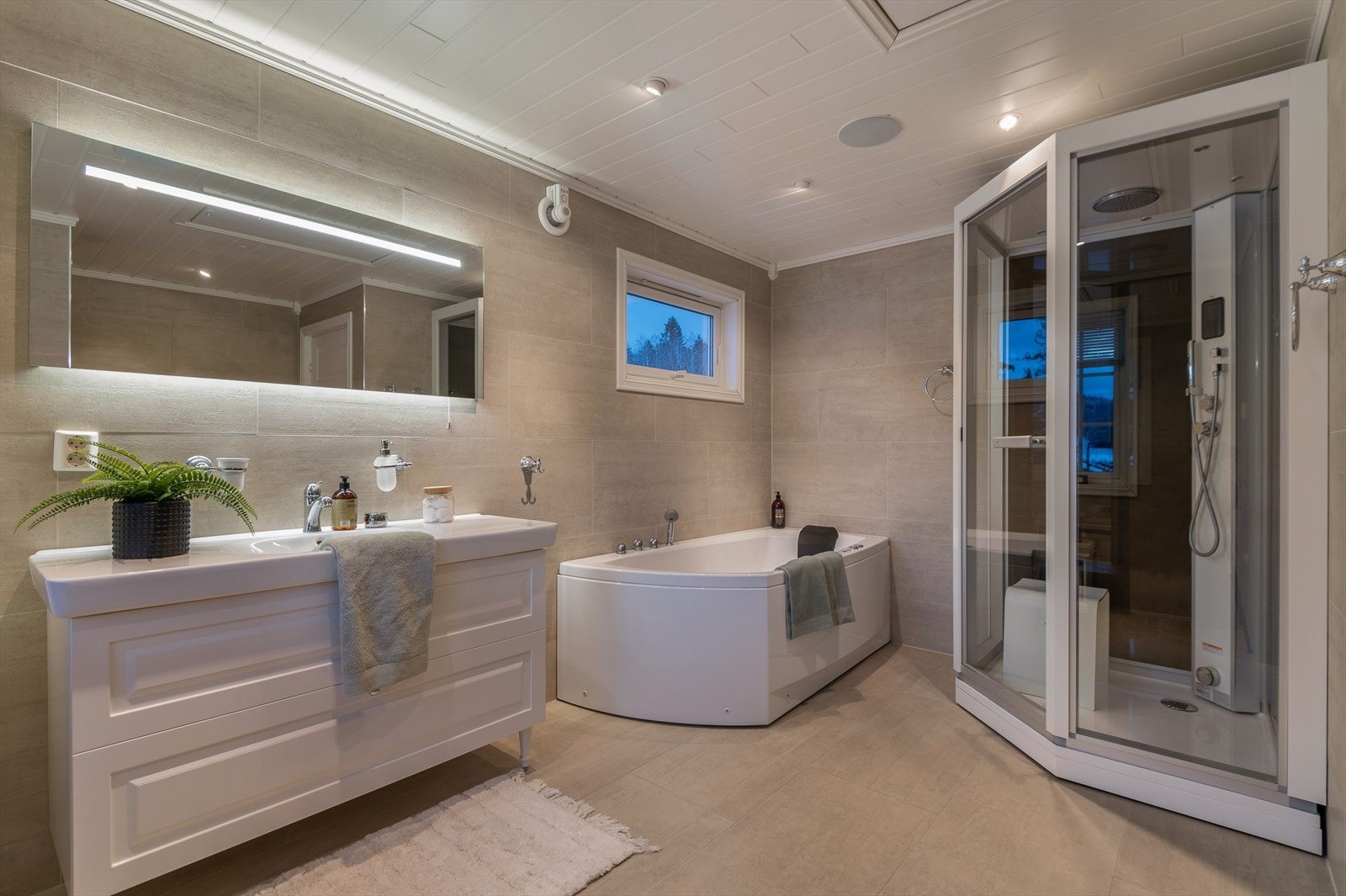 Innredningen består av flis på gulv og vegger, boblebadekar, stort dusjkabinett, opplegg for vaskemaskin og servant med blandebatteri. Galleribilde