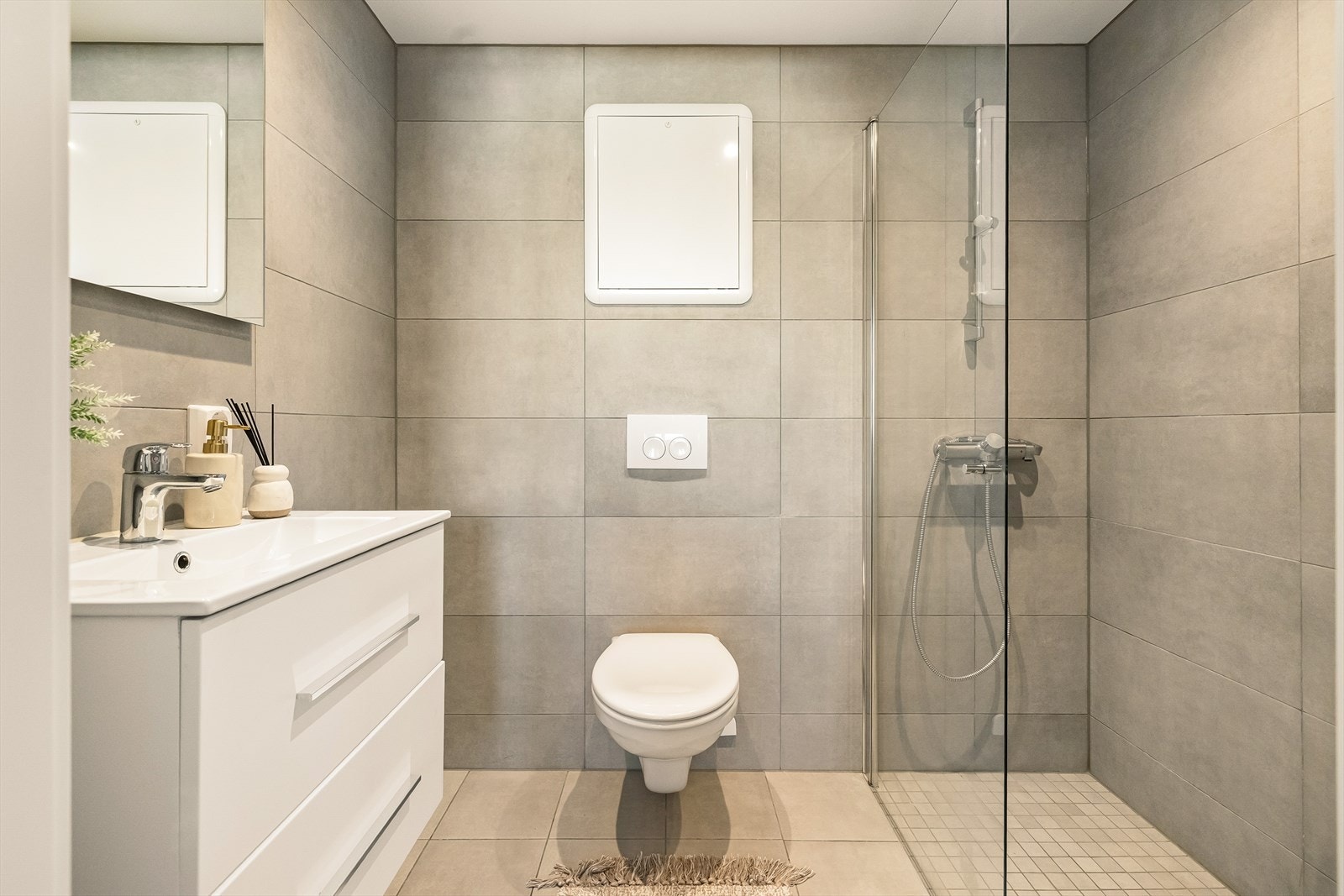 Pent og svært tidsriktig baderom med vegghengt toalett, servantskap og dusjhjørne. Galleribilde