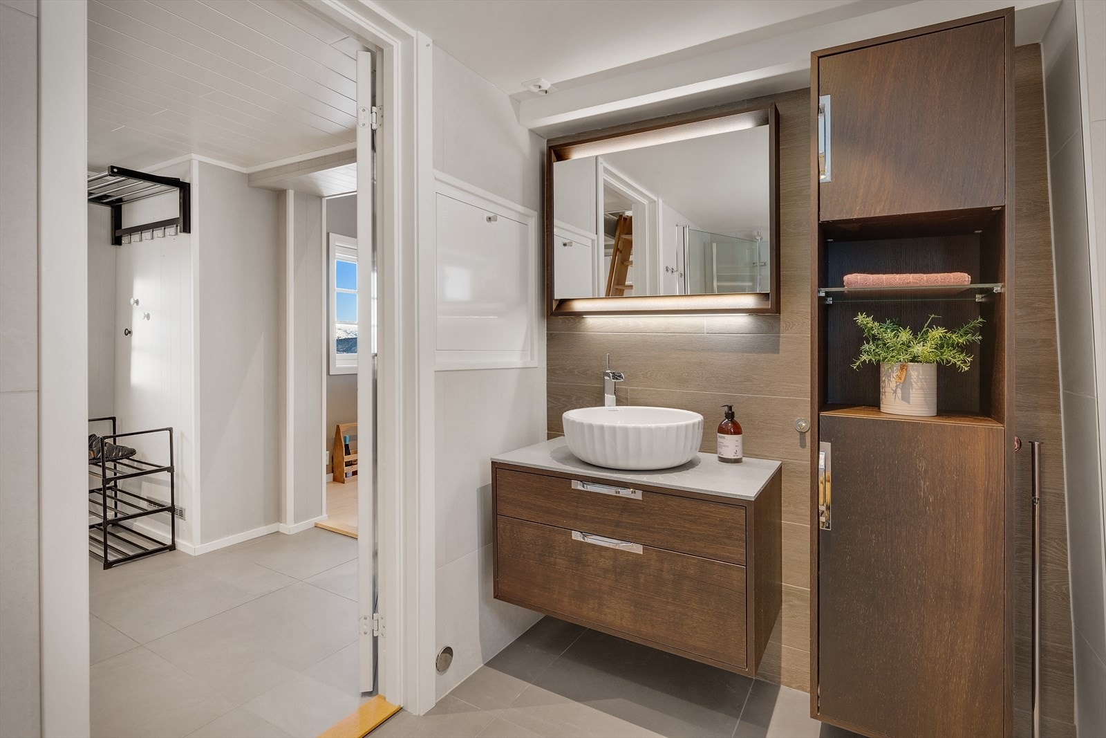 Badet er utstyrt med foldedører i dusj, toalett og baderomsinnredning med servant, samt belyst speil Galleribilde