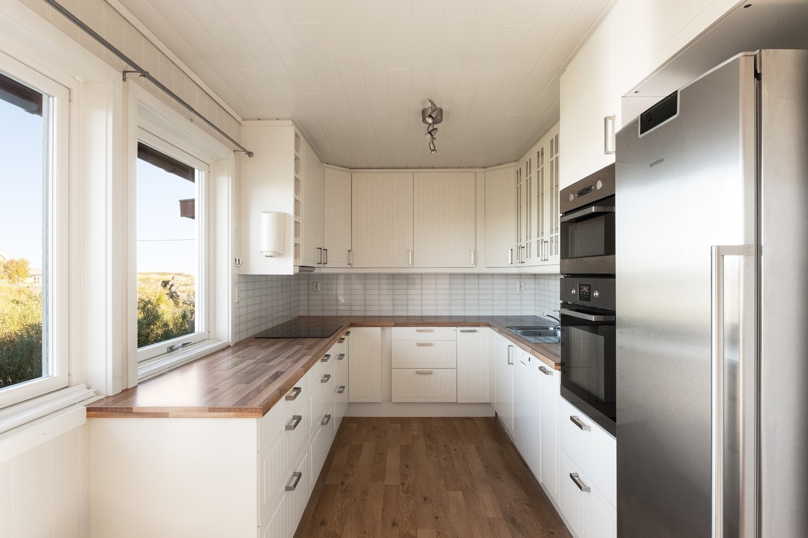 Hvit, tidløs kjøkkeninnredning med integrerte hvitevarer. Galleribilde