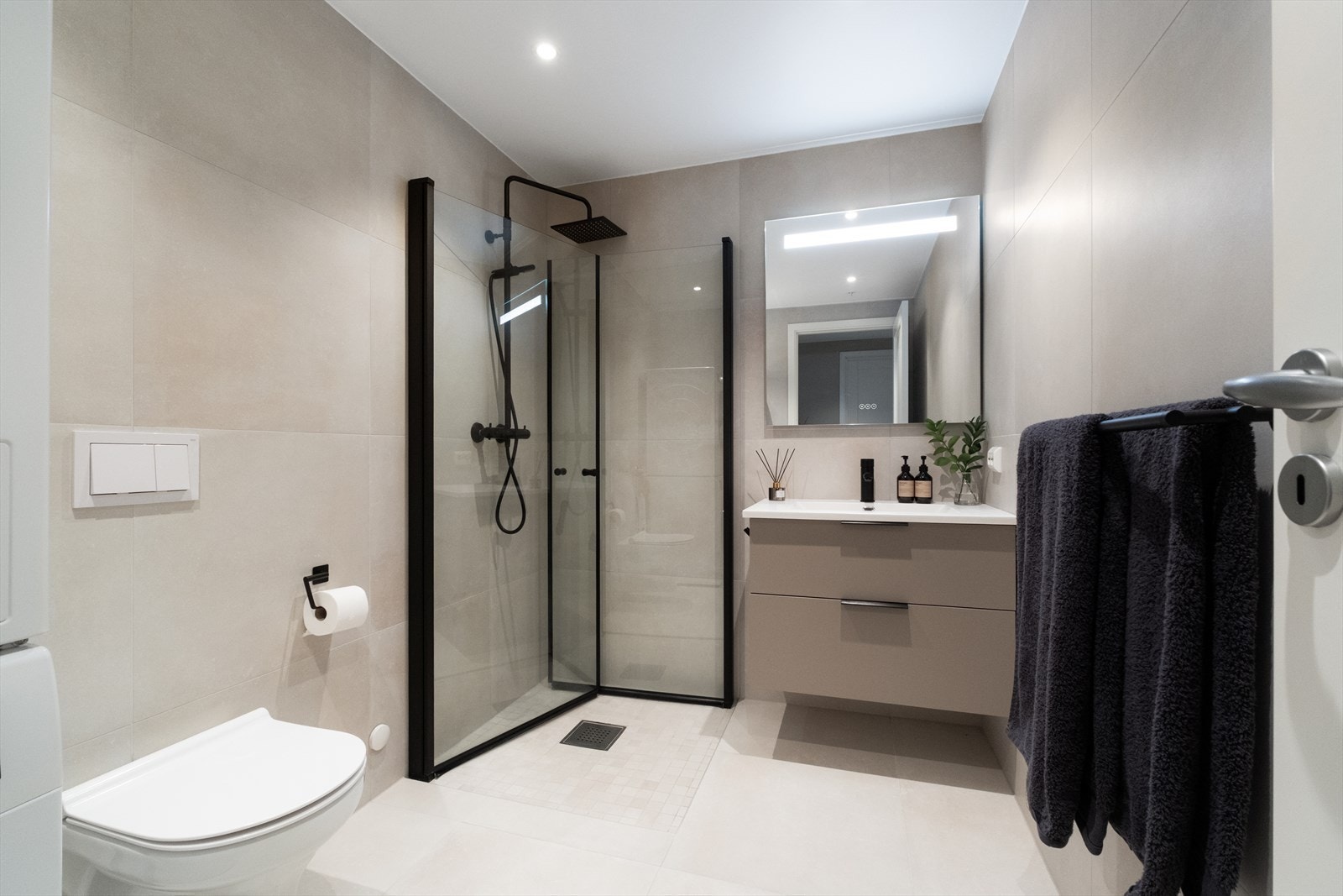 Rommet er utstyrt med vegghengt wc, dusjhjørne med glassvegger og tropedusj, servant med underskap og speil med integrert belysning. Galleribilde