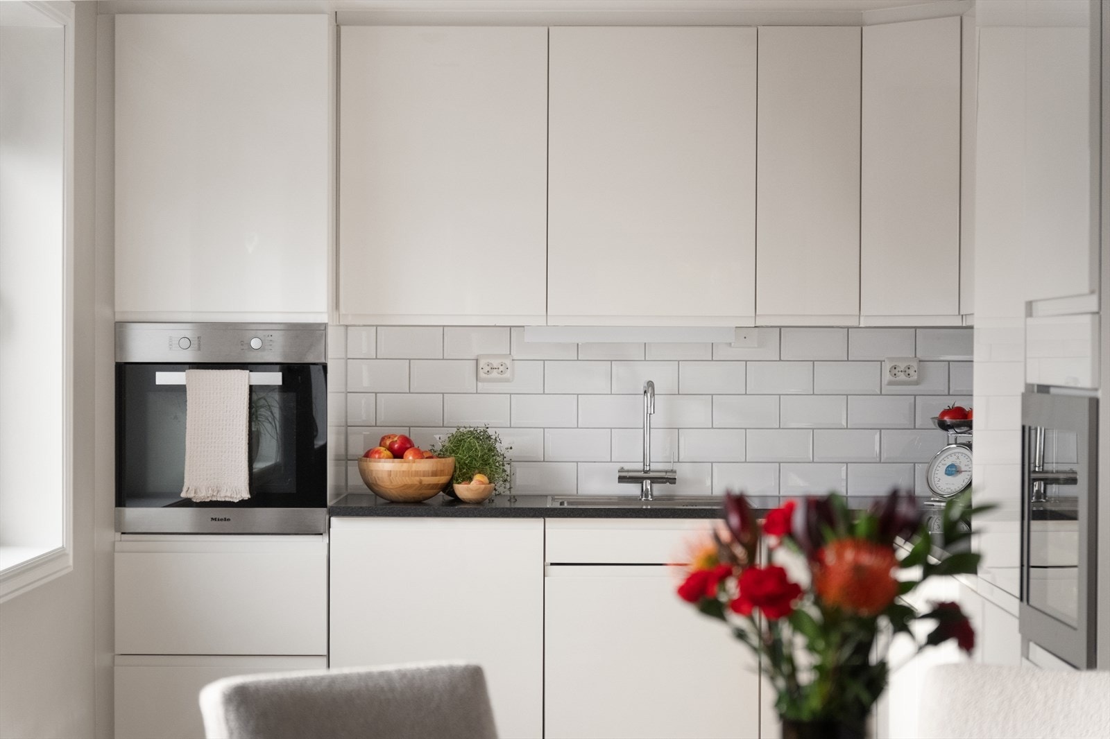 Blanke fronter og flislagt bakvegg gir et stilrent uttrykk til kjøkkenet. Galleribilde