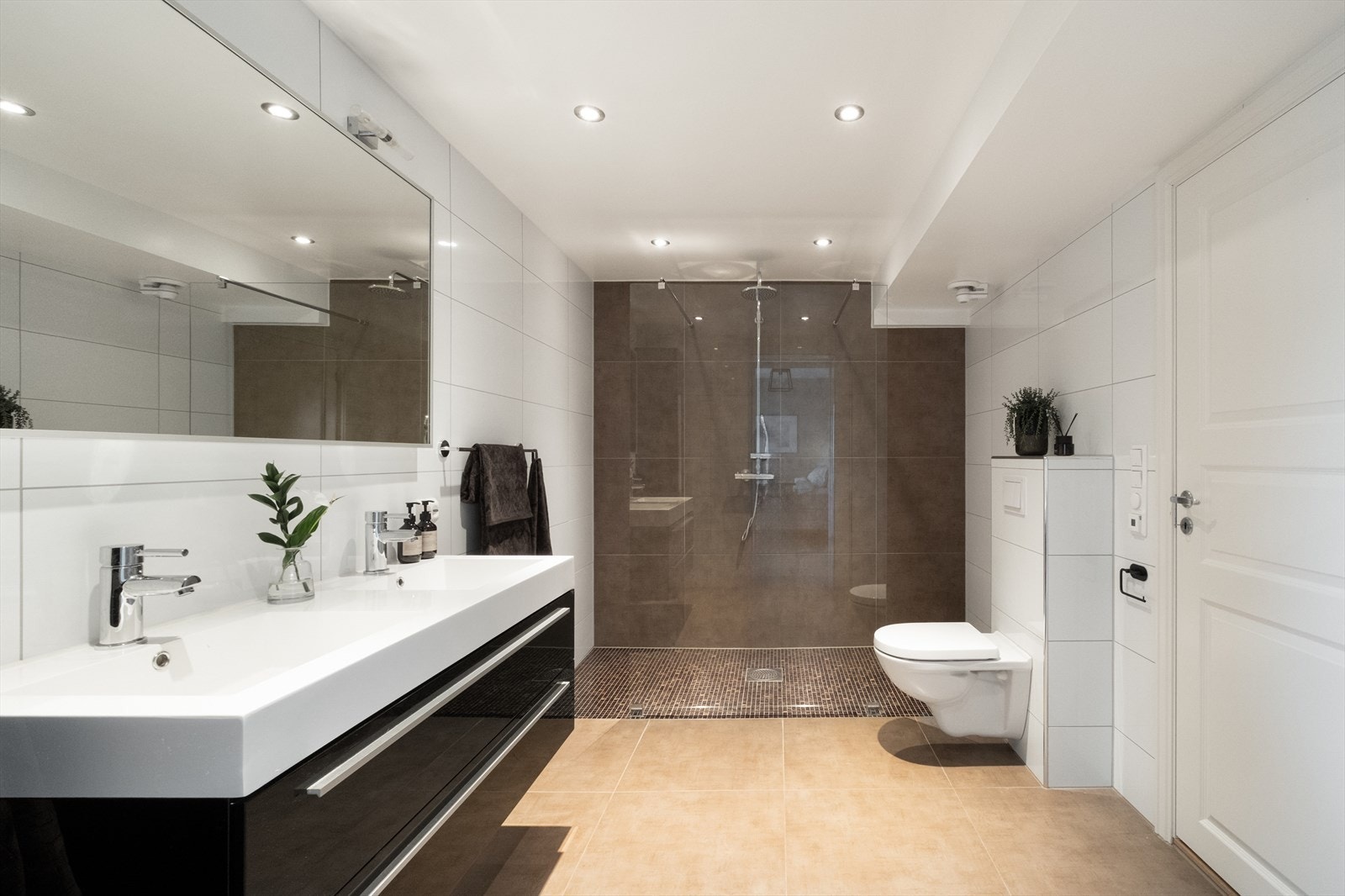 Badet er romslig, og utstyrt med vegghengt wc, heldekkende, dobbel servant med underskap, og stor dusj med tropedusj og glassvegg. Galleribilde