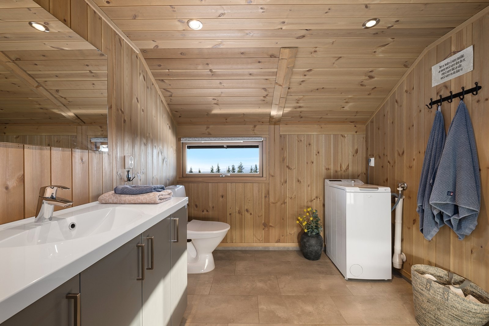 Pent bad/wc har baderomsinnredning med glatte fronter i lun gråtone. Plass til vaskemaskin. Gulvmontert WC og dusj. Galleribilde