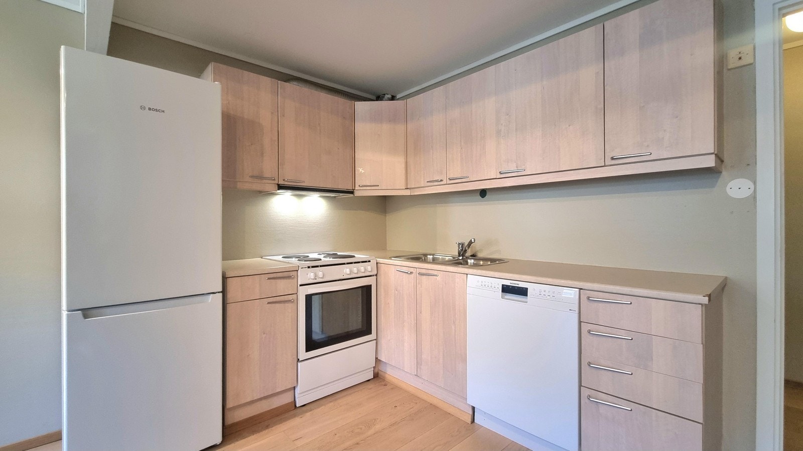 Kjøkken med hvitevarer, mye skap og benkeplass Galleribilde