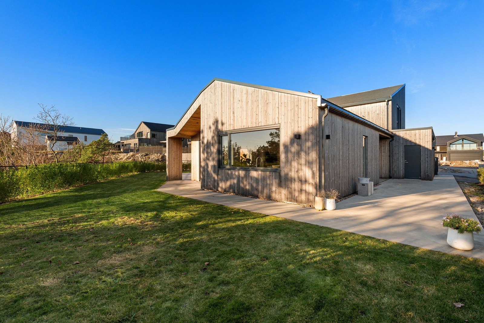 Pent opparbeidet tomt med både støpt platting, gressplen og terrasse med accoya terrassebord Galleribilde
