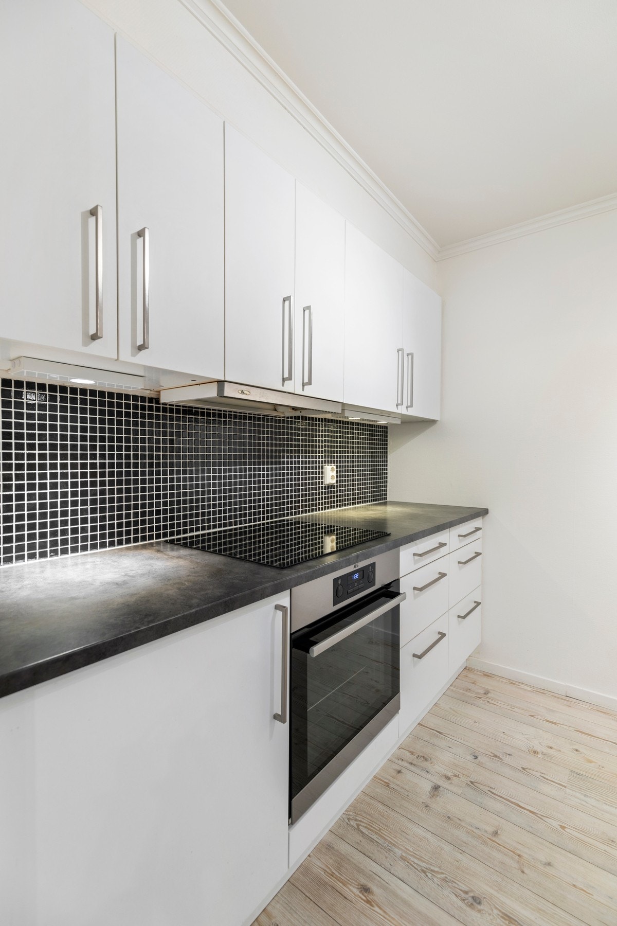 Kjøkkenet har innredning i hvite, slette fronter, laminat benkeplate med flis mot overskap, ventilator, samt integrerte hvitevarer; stekeovn, platetopp og oppvaskmaskin. Galleribilde