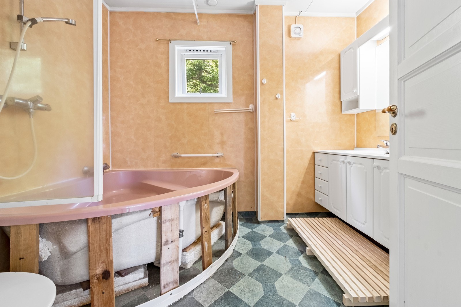 Bad i hovedetasjen har hjørnebadekar, wc og hvit baderomsinnredning med heldekkende servant. Galleribilde